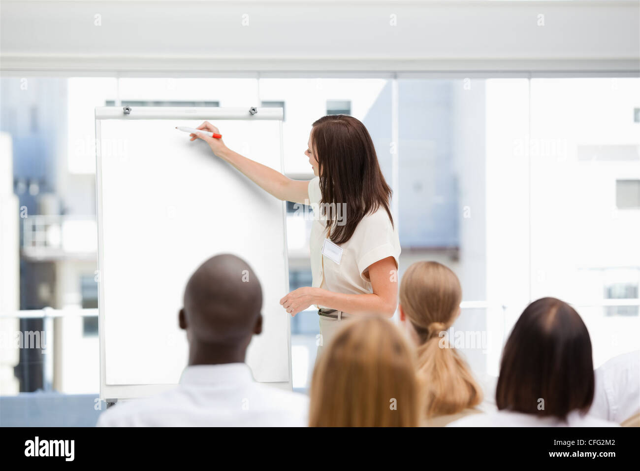 Femme écrivant sur un tableau tout en étant regardé par un public Banque D'Images