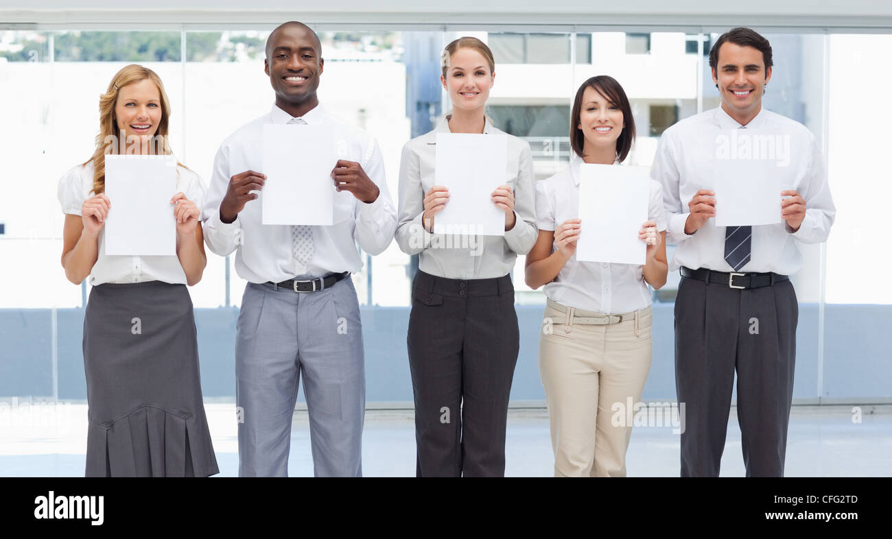 Smiling business team holding draps blancs en face d'eux Banque D'Images