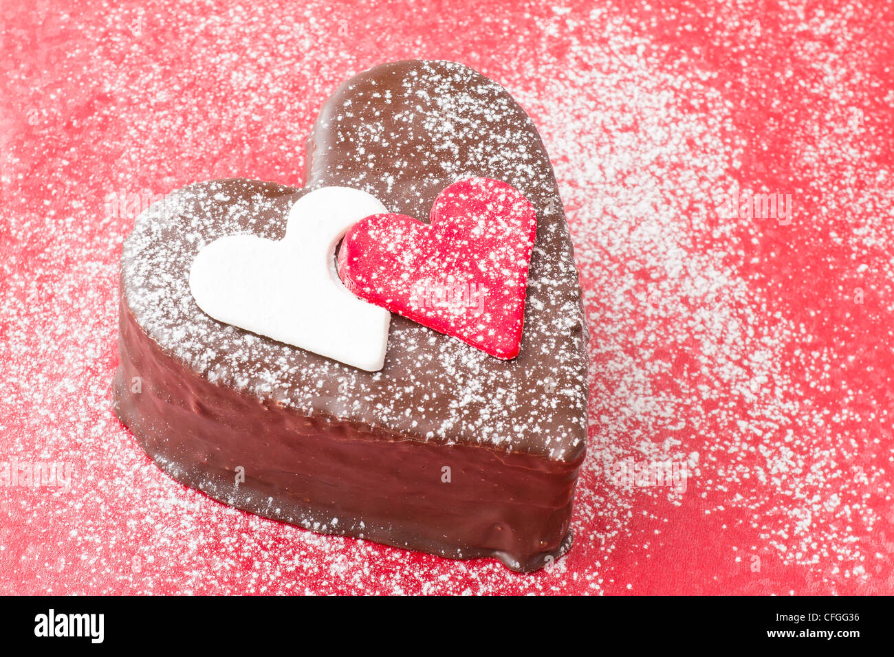 En forme de coeur une tranche de gâteau de chocolat sur fond rouge Banque D'Images