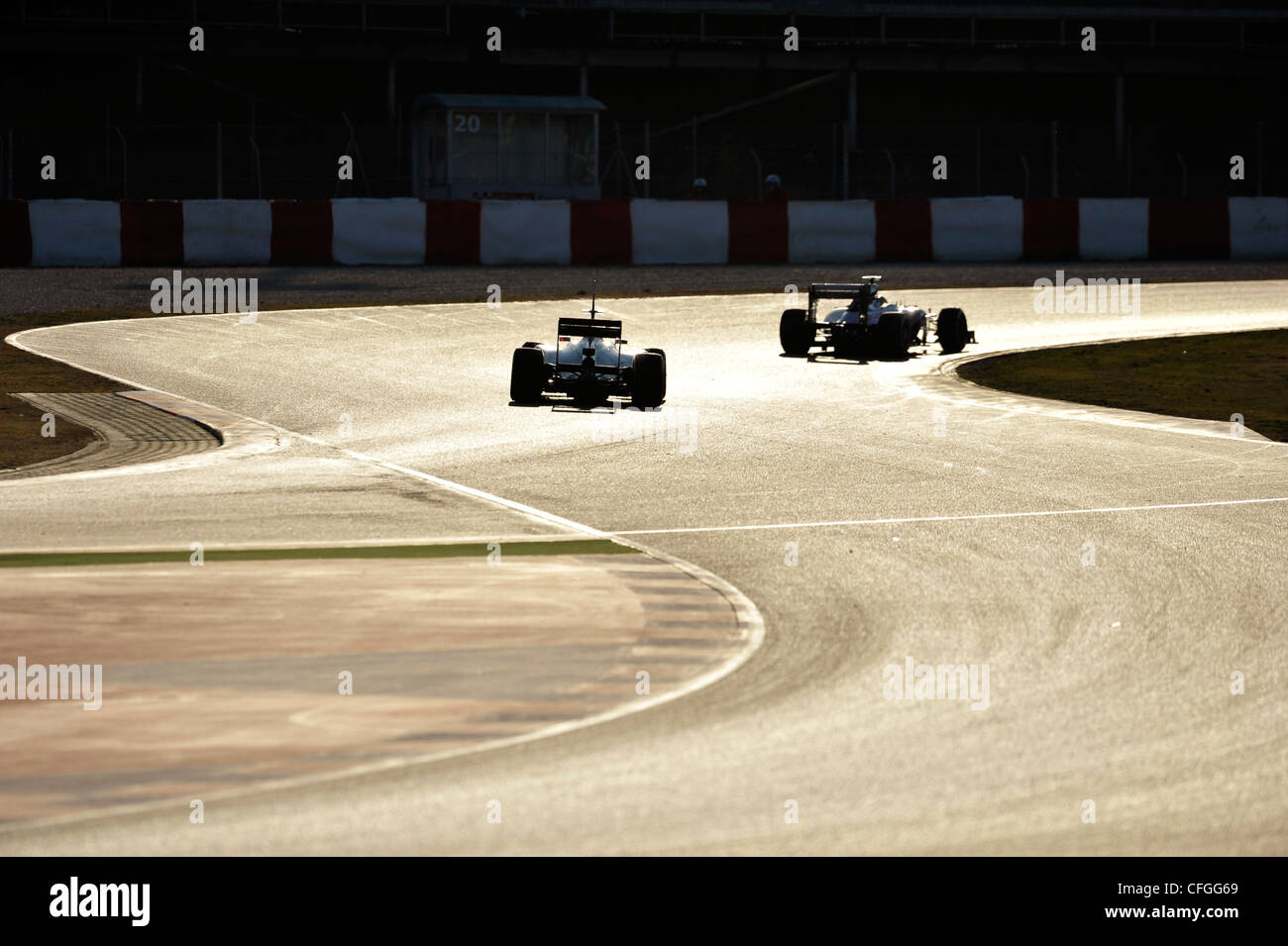 2 voitures en courbe en contre-jour au cours de la Formule Un session de test sur circuit de Catalogne, Espagne Banque D'Images