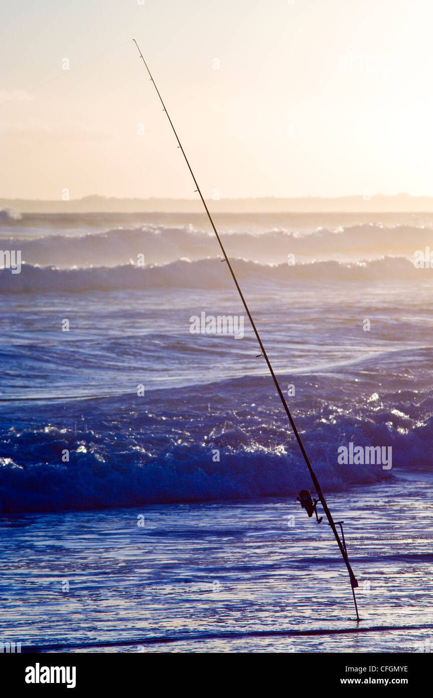 Une canne à pêche et le moulinet de surf dans les eaux peu profondes en attente d'un crochet de poisson. Banque D'Images