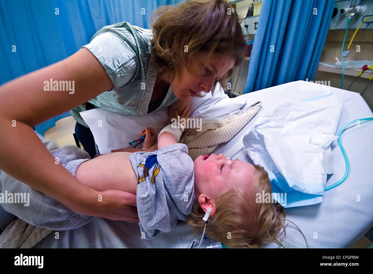 Une mère réconforte son fils en difficulté dans la récupération après chirurgie de l'oreille. Banque D'Images