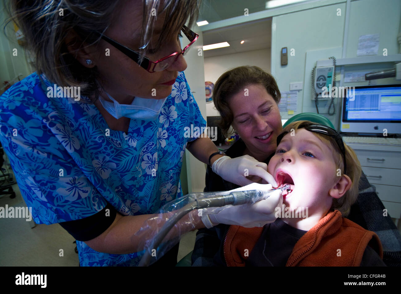 Un dentiste polit les dents d'un garçon à son premier contrôle. Banque D'Images