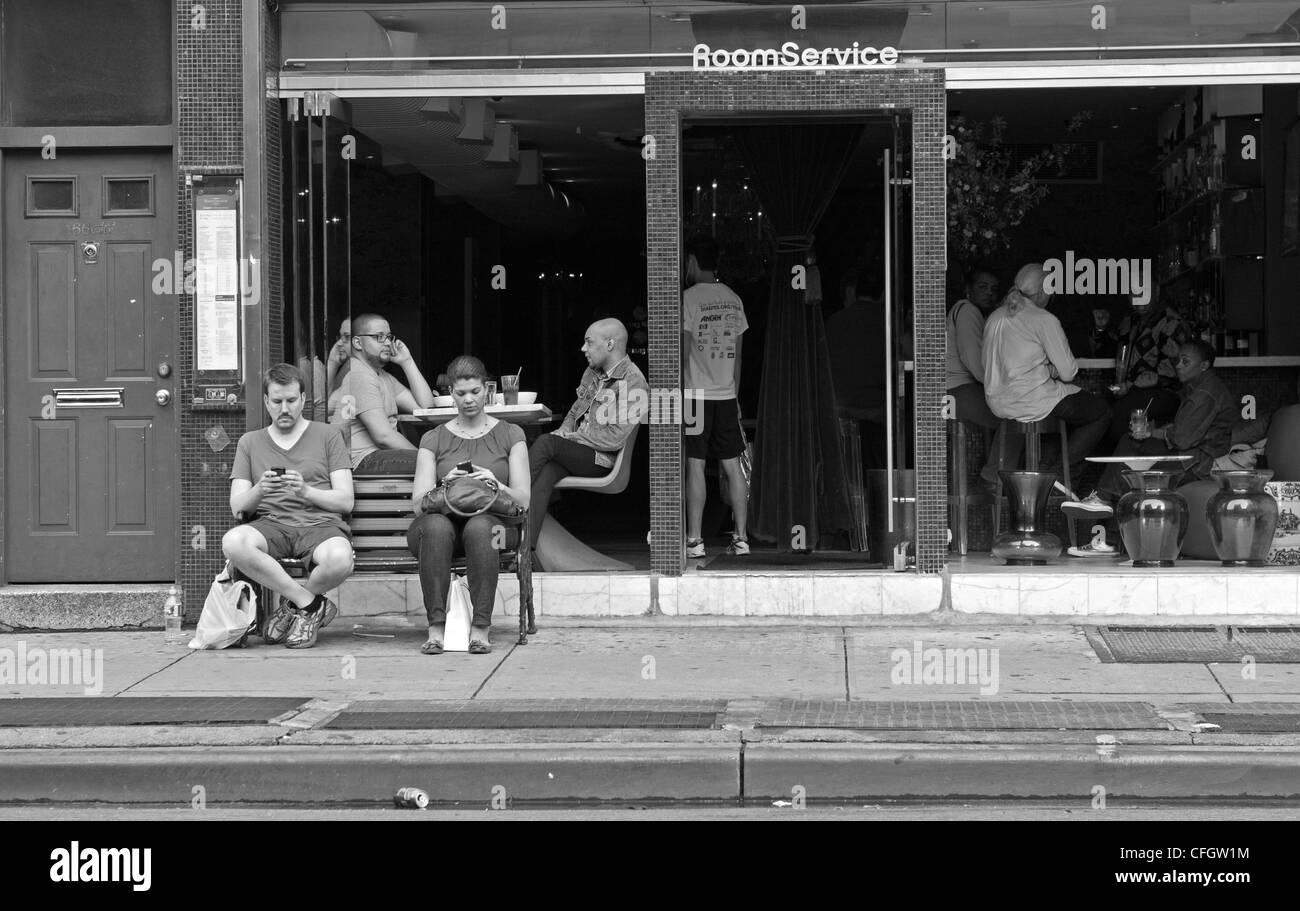 2 personnes s'asseoir sur un banc tout en envoyant dans la ville de New York. Banque D'Images