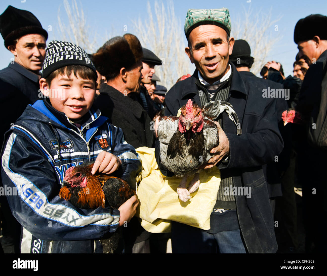 Tenant leurs coqs dans un marché hebdomadaire dans le Xinjiang. Banque D'Images