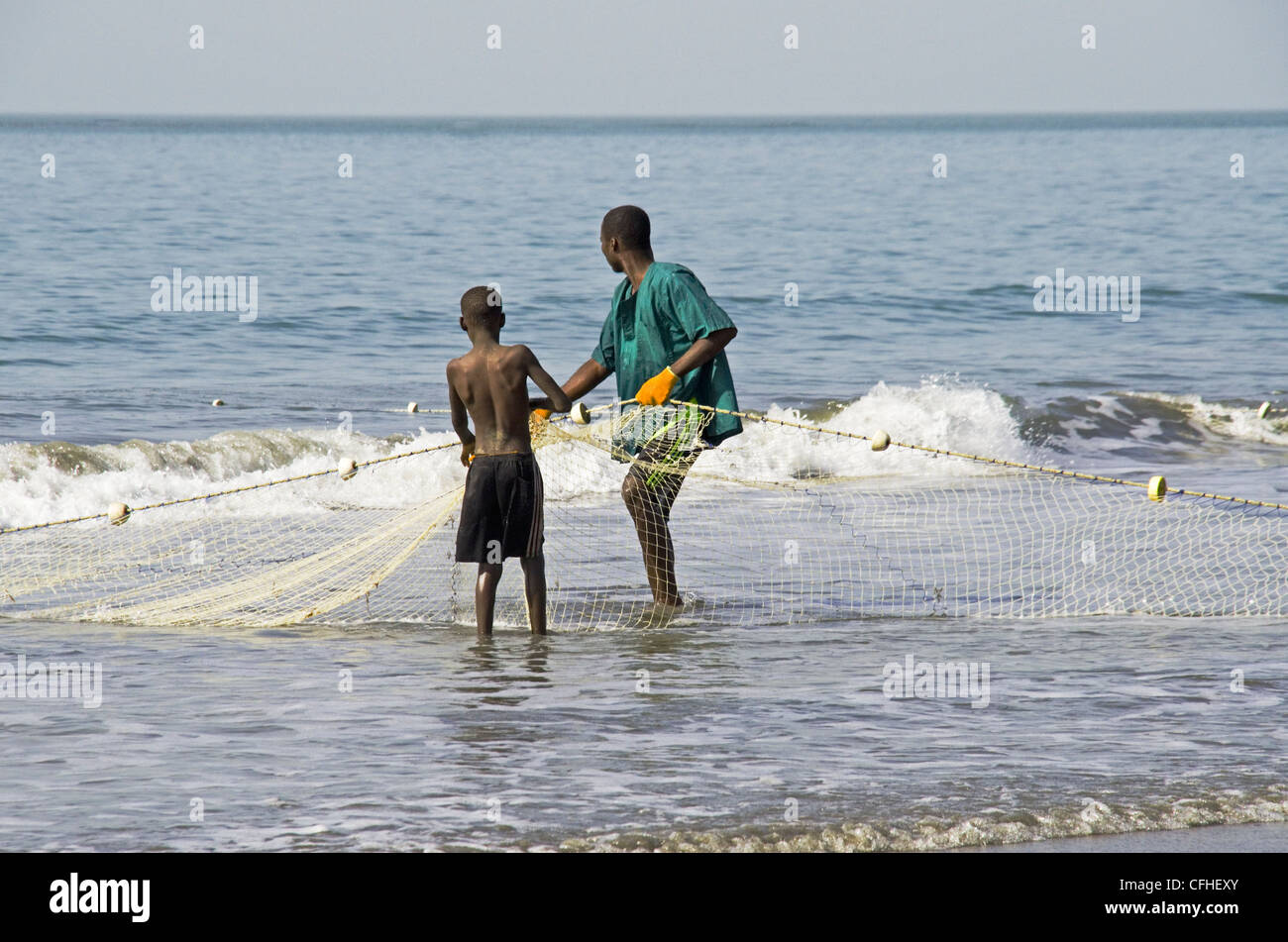 Un jeune garçon de la Gambie l'apprentissage des techniques de la pêche de l'un des aînés de village de Kololi Gambie Afrique de l'ouest Banque D'Images