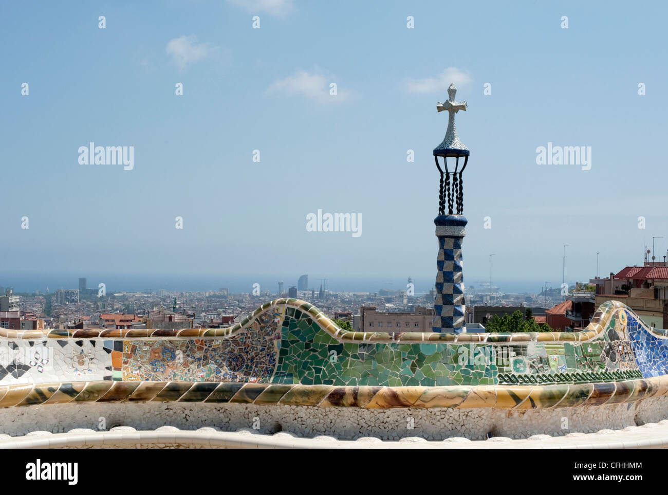 Le serpent de mer banc en mosaïque de la terrasse principale du Parc Guell d'une croix et de Barcelone dans la distance. Banque D'Images