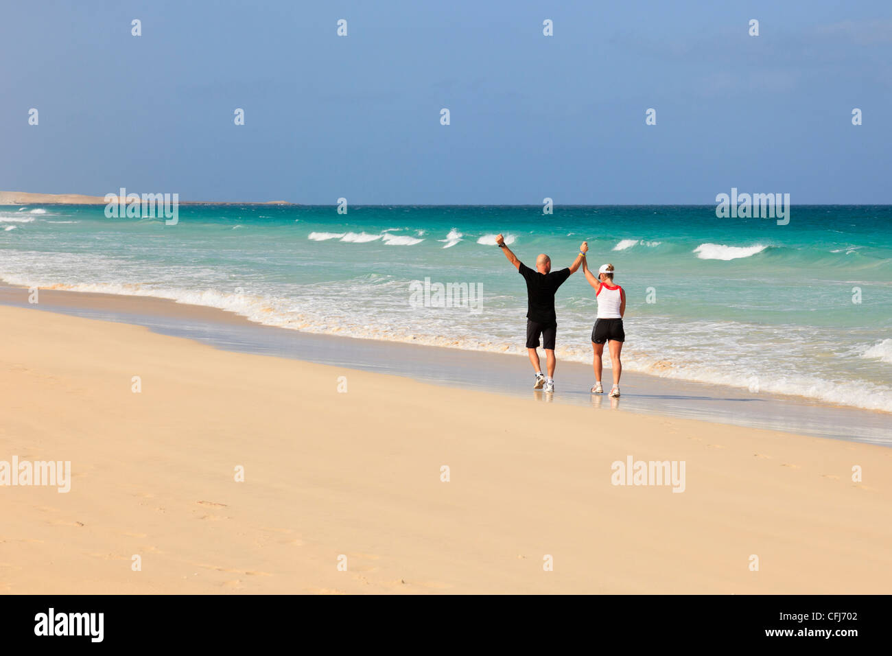 Deux personnes s'encoudent le long du rivage à côté d'une mer turquoise sur une plage de sable blanc par une journée ensoleillée. Praia de Chaves Boa Vista Iles du Cap-Vert Banque D'Images