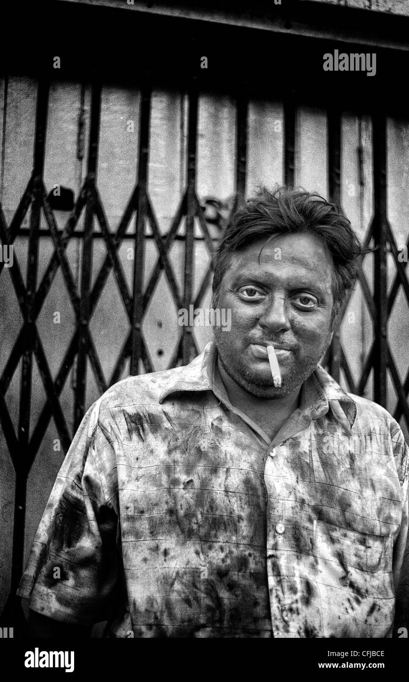 Portrait d'un homme fumant une cigarette dans les rues de Calcutta durant la célébration de la fête de Holi, Inde. Banque D'Images