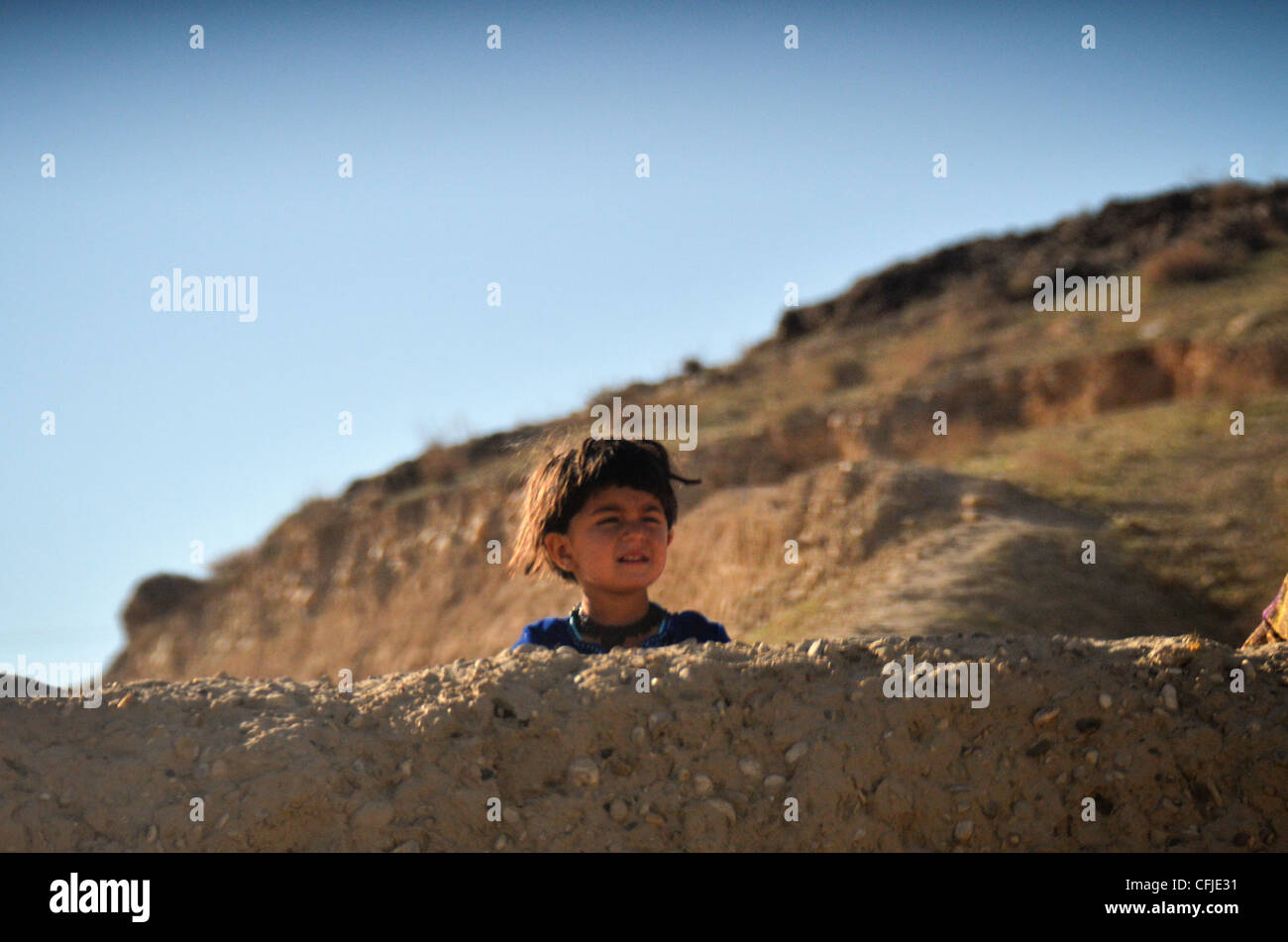 Un enfant afghan regarde un bataillon de logistique de combat 4, 1er groupe de logistique de marine (Forward), un convoi passe sur les routes au nord de Sangin en mars 5. La patrouille de logistique de combat a livré des fournitures aux bases d'opérations de combat à l'avant, tenues par les Marines de l'équipe de combat régimentaire 6. Banque D'Images