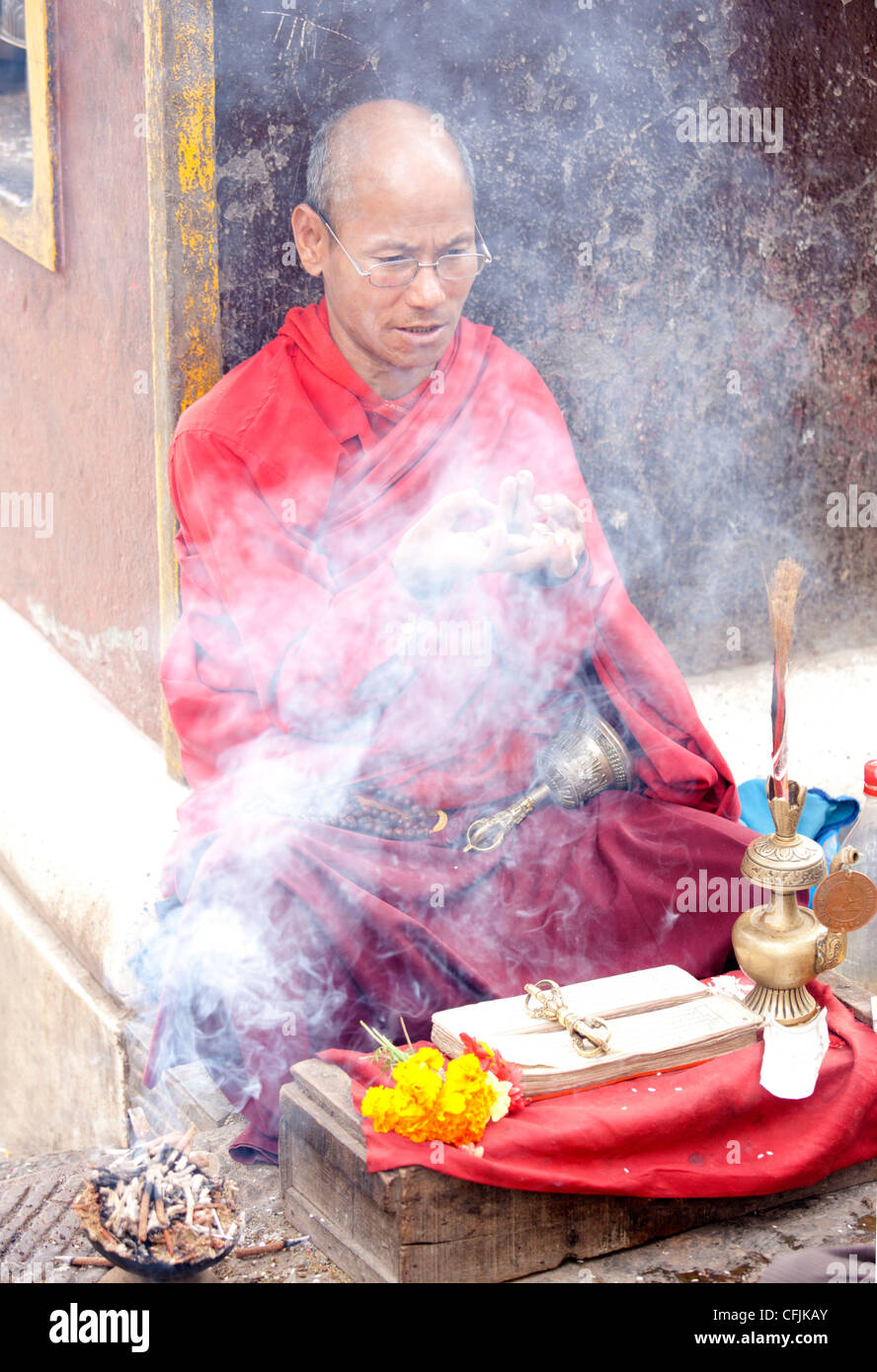 Le moine bouddhiste près de Swayambhunath offrant à bénir les gens à un autel, Katmandou, Népal, Asie Banque D'Images