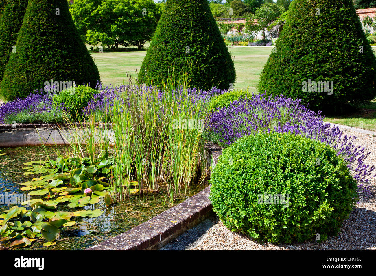 Une partie de l'étang ornemental entouré de lavandes et d'un jardin anglais en topiaire, Littlecote Manor dans le Berkshire, Angleterre, RU Banque D'Images