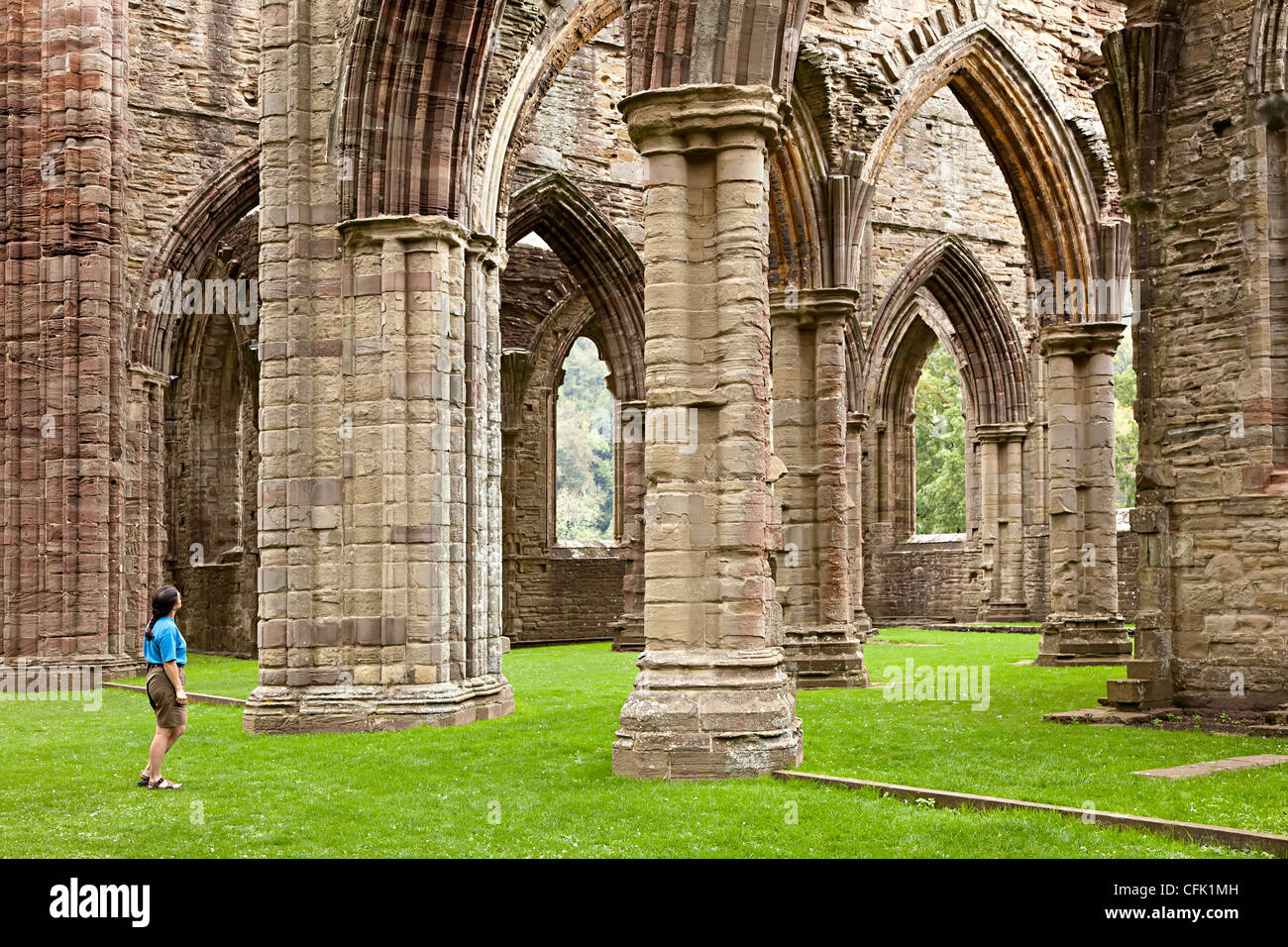 Femme regardant les ruines de l'abbaye de Tintern, Pays de Galles, Royaume-Uni Banque D'Images