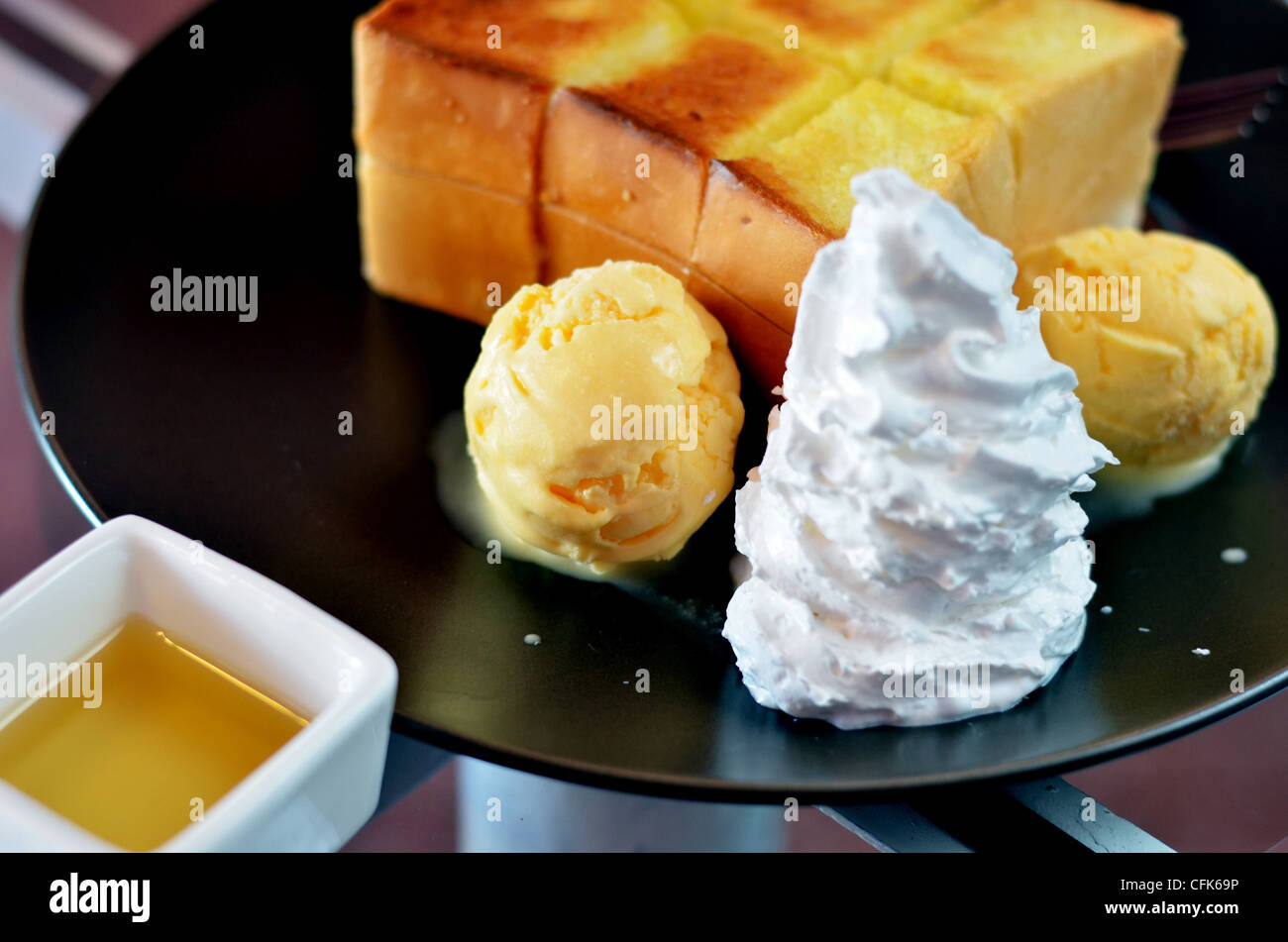 Toast et crème fouettée avec de la crème de glace à la vanille servi avec sauce au miel Banque D'Images