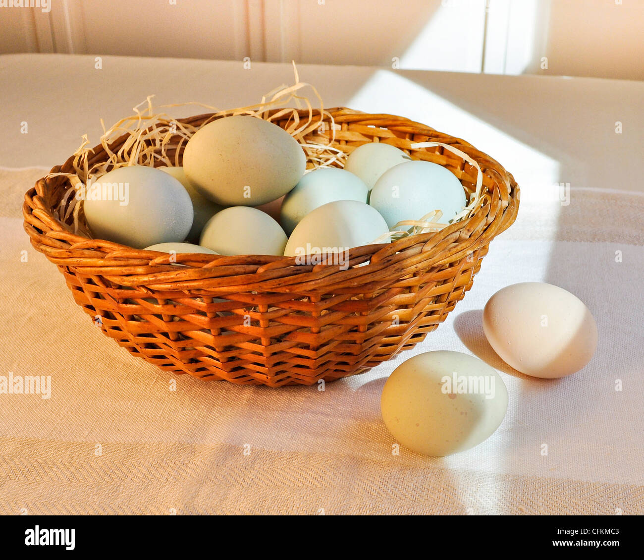 Un bol d'œufs de poule de couleur pastel dans un panier de Pâques sur lin tissé. Banque D'Images