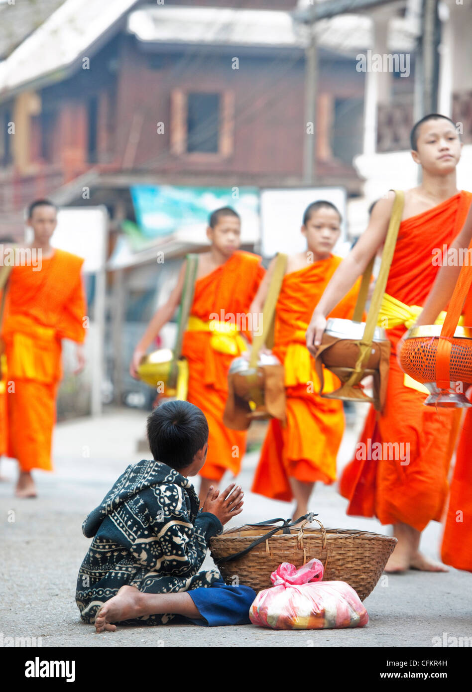 Jeune garçon mendier de la nourriture de moines qui ont été donné de la nourriture chaque jour, à l'aumône la cérémonie de remise des prix à Luang Prabang, Laos Banque D'Images