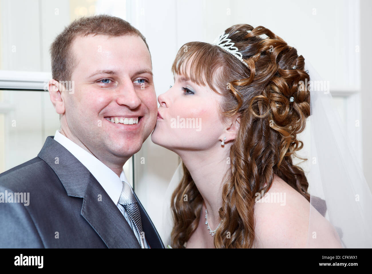 Young Caucasian couple mariage russe. S'embrasser la mariée le marié dans la joue Banque D'Images