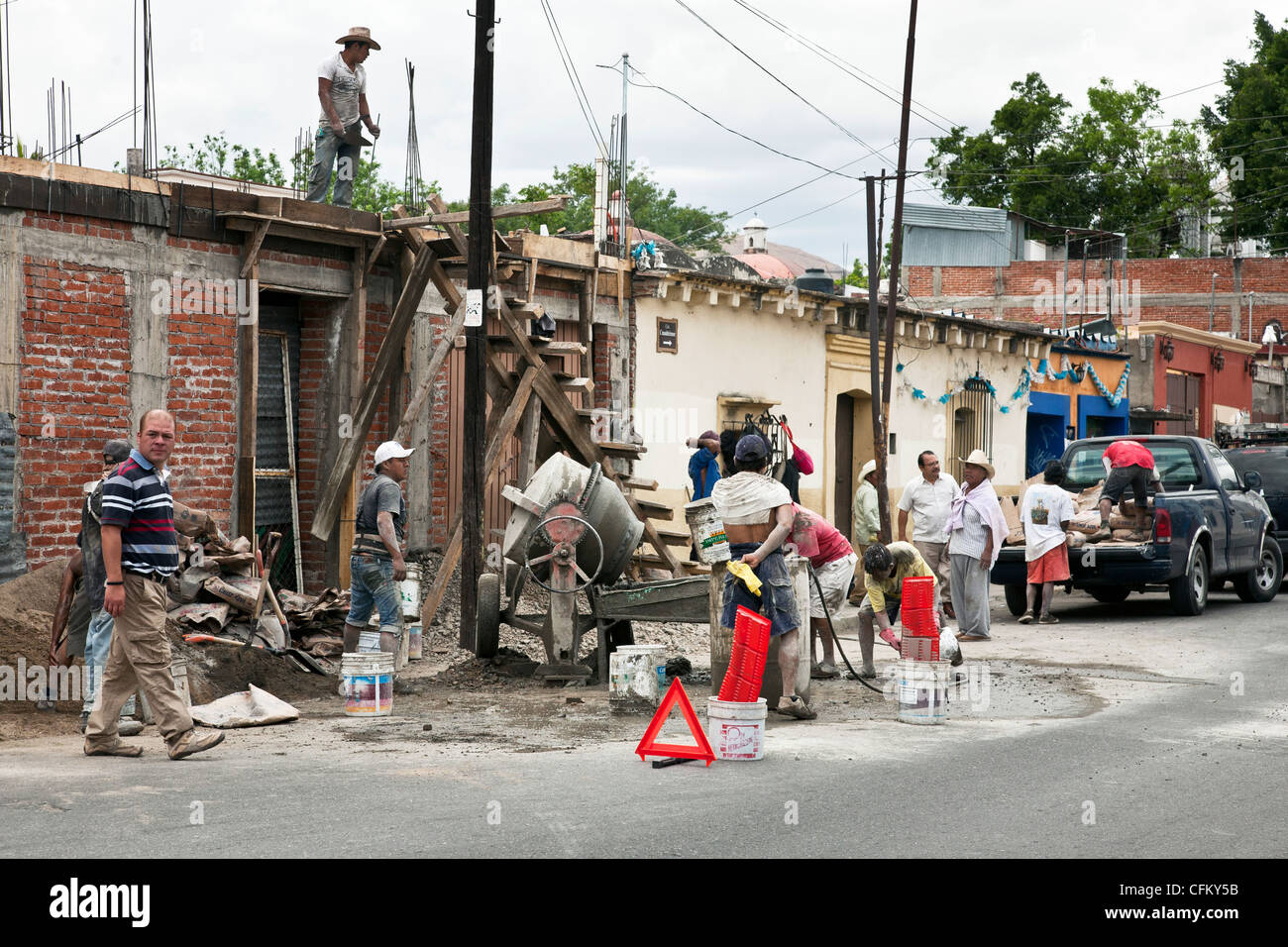 Enduit d'ouvriers occupés de la poussière de ciment autour de la grappe part powered bétonnière at construction site avec superviseur Oaxaca Mexique Banque D'Images