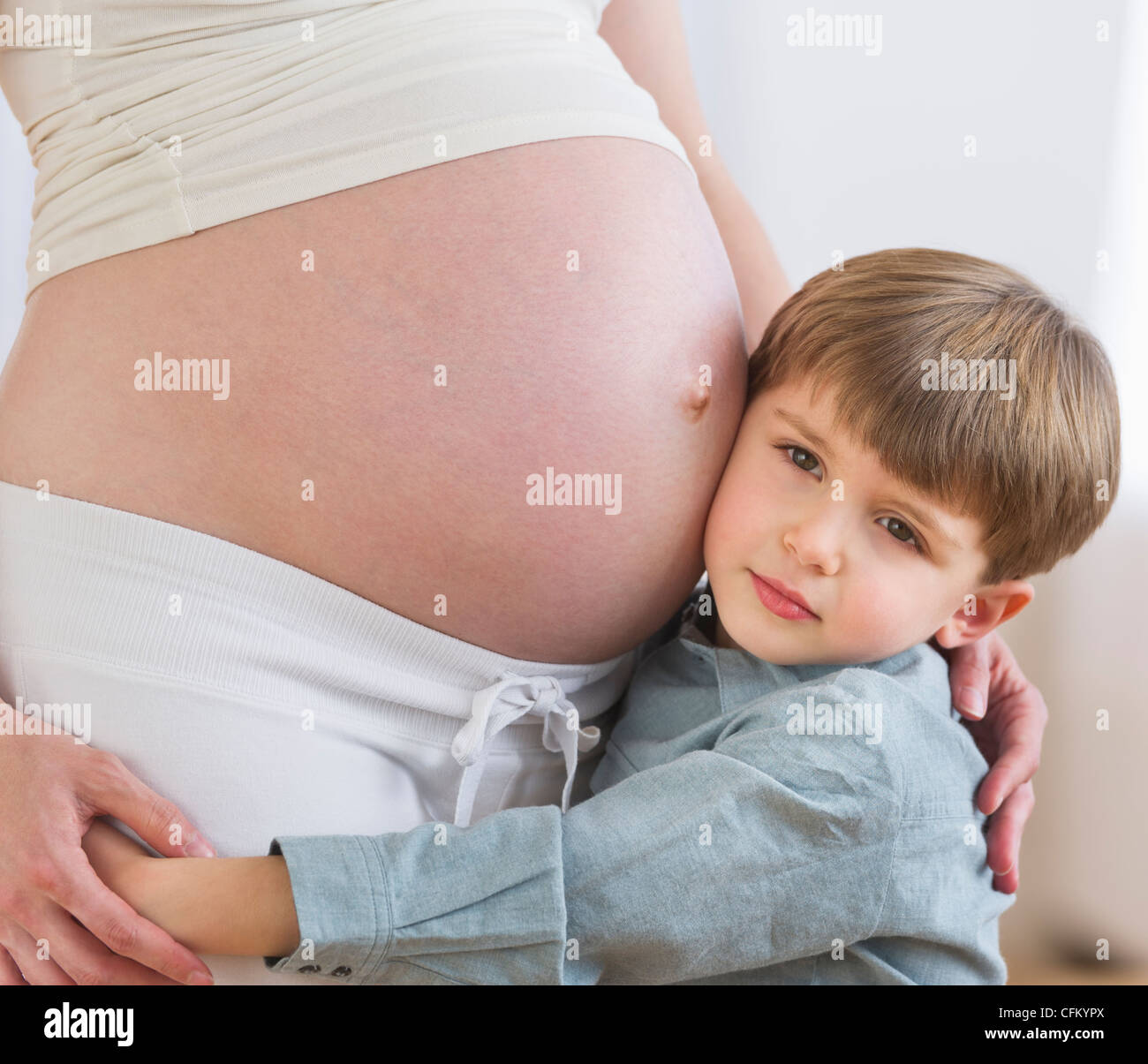 USA, New Jersey, Jersey City, Boy (4-5) mettant l'oreille à ventre de la mère enceinte Banque D'Images