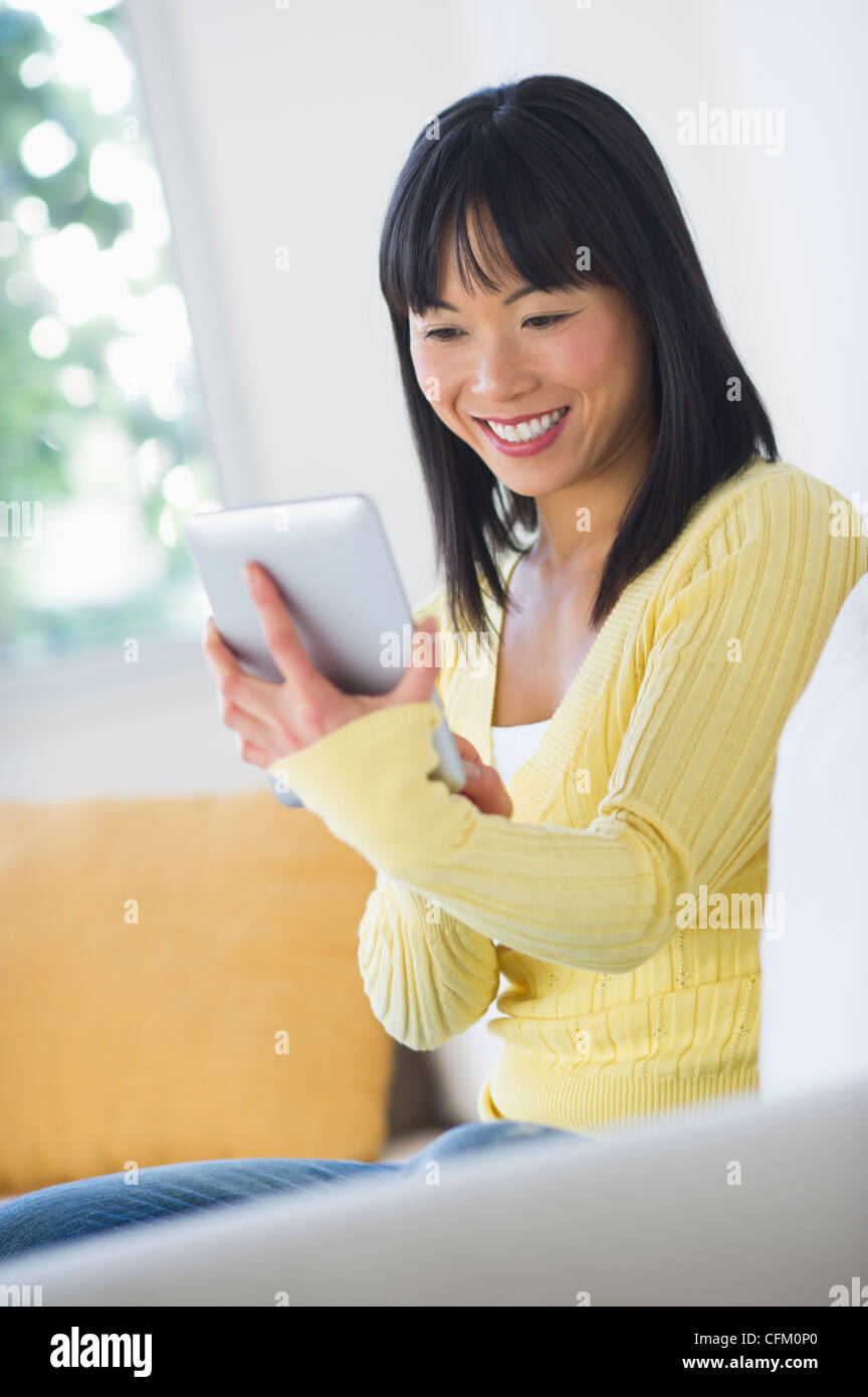 USA, New Jersey, Jersey City, Smiling woman sitting on sofa and using digital tablet Banque D'Images