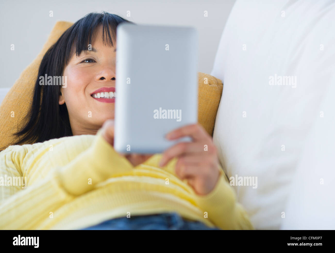 USA, New Jersey, Jersey City, Smiling woman lying on sofa and using digital tablet Banque D'Images