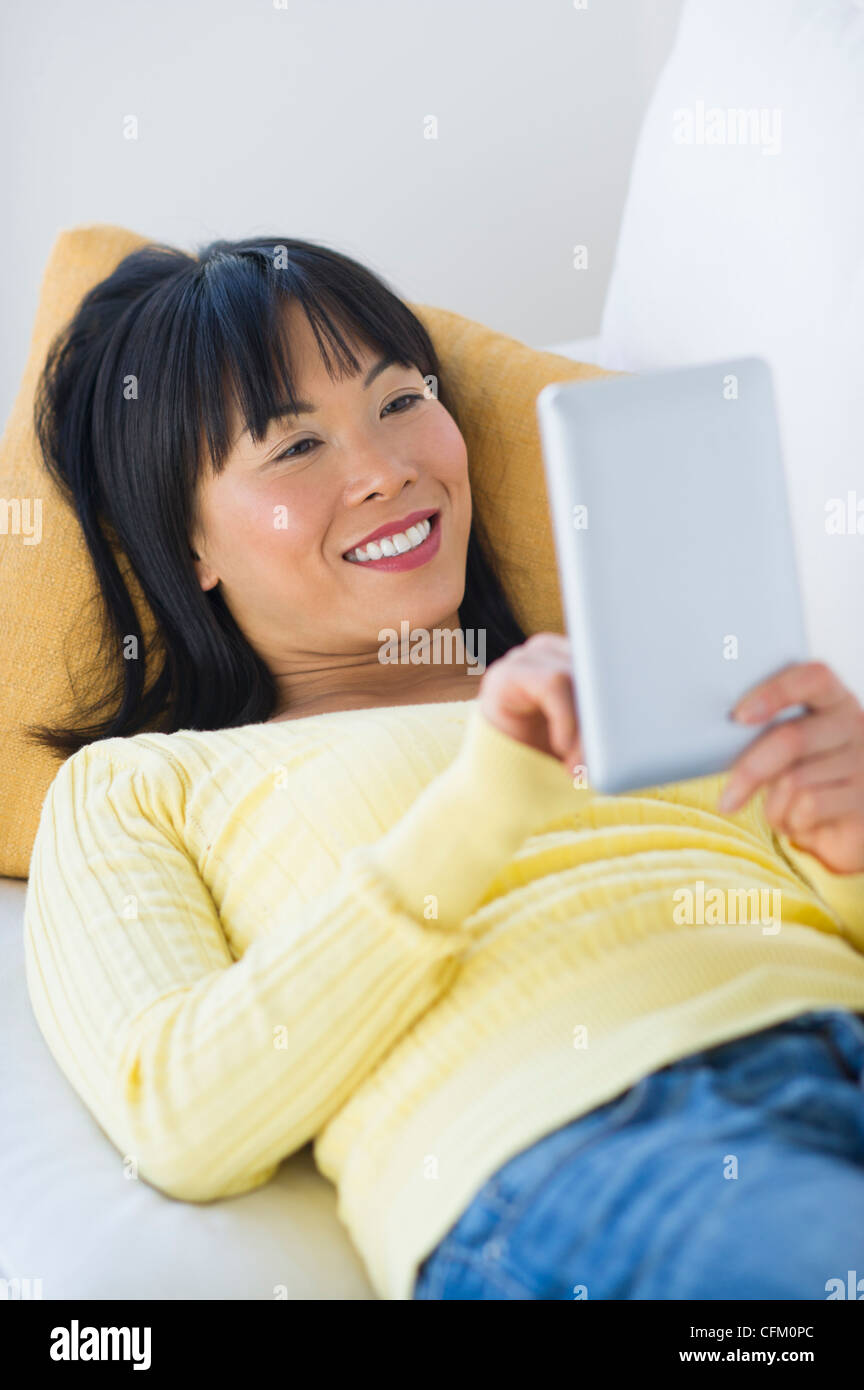 USA, New Jersey, Jersey City, Smiling woman lying on sofa and using digital tablet Banque D'Images