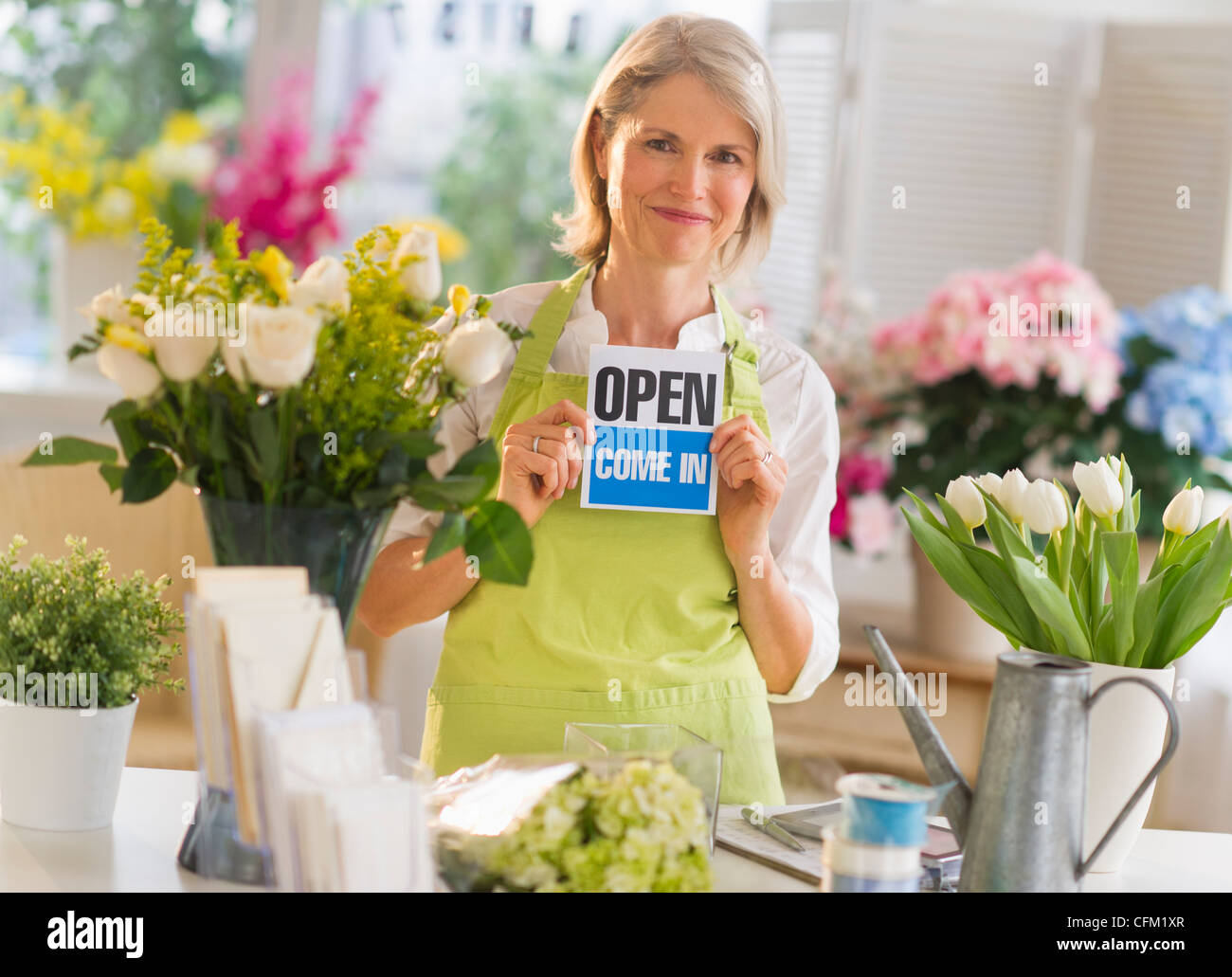 USA, New Jersey, Jersey City, Senior female florist montrant open sign Banque D'Images
