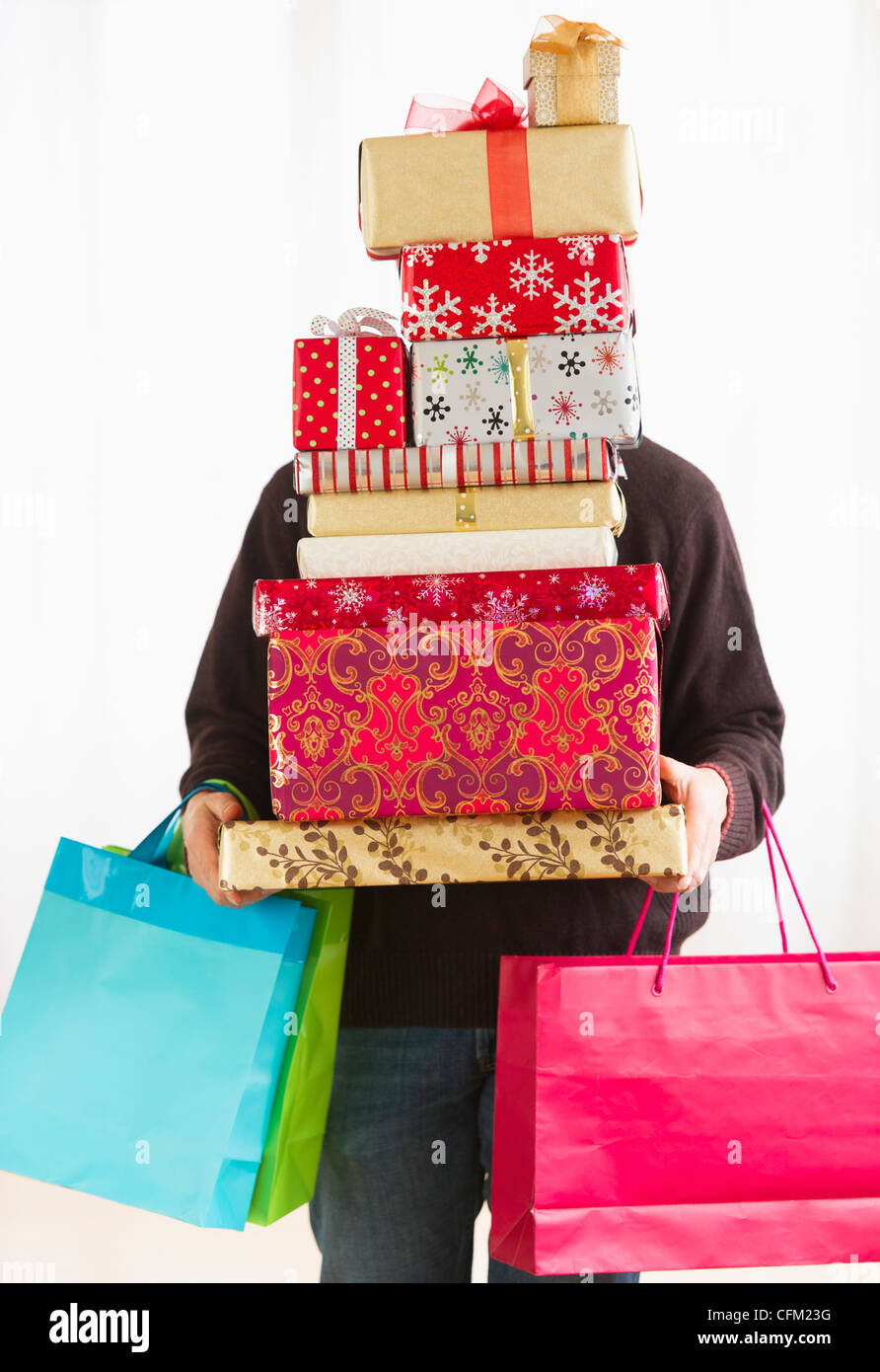 Man carrying pile de cadeaux de Noël, studio shot Banque D'Images