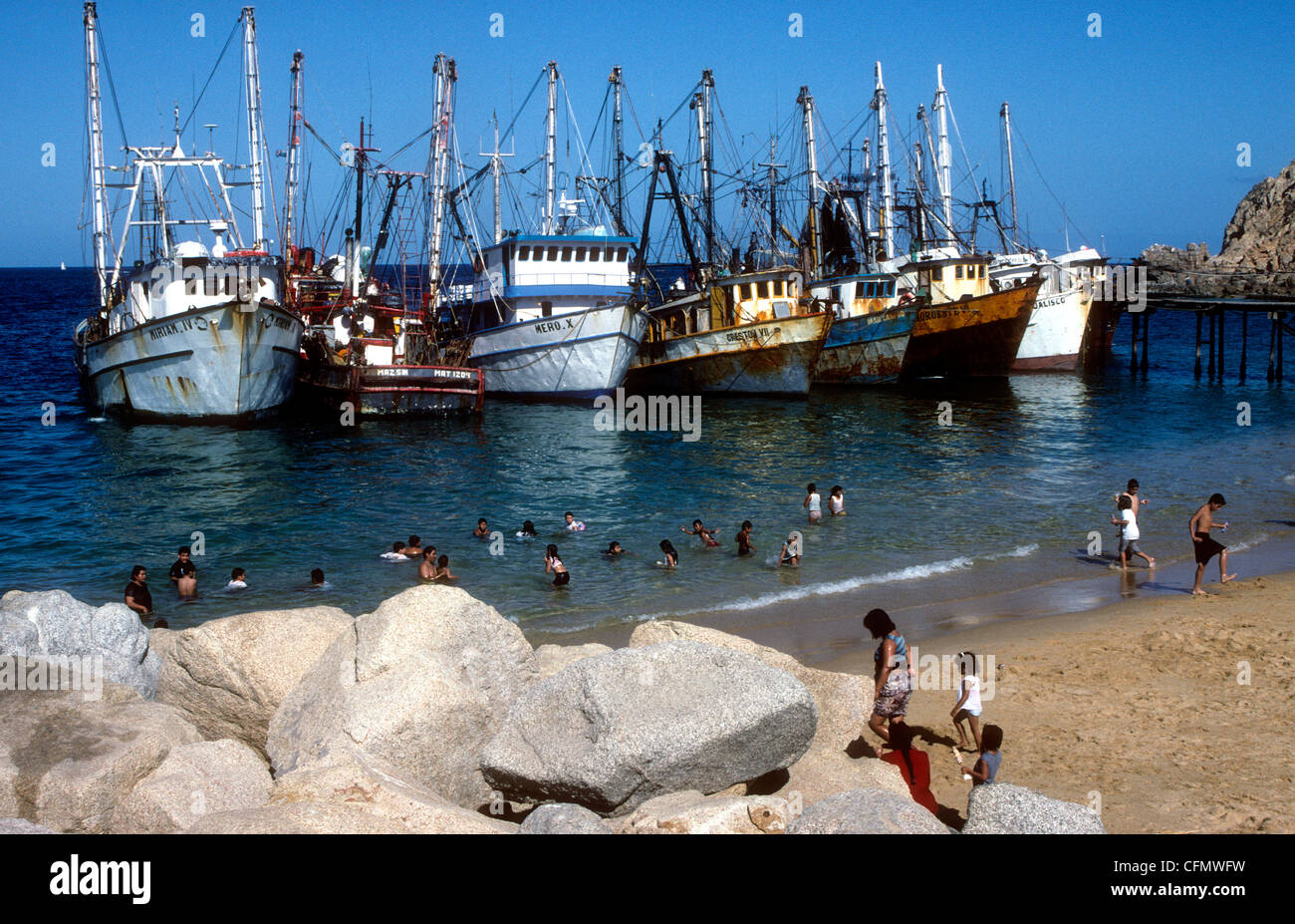 Les gens se baigner à côté de bateaux de pêche amarrés à une plage de Cabo San Lucas, Baja California Sur, Mexique Banque D'Images