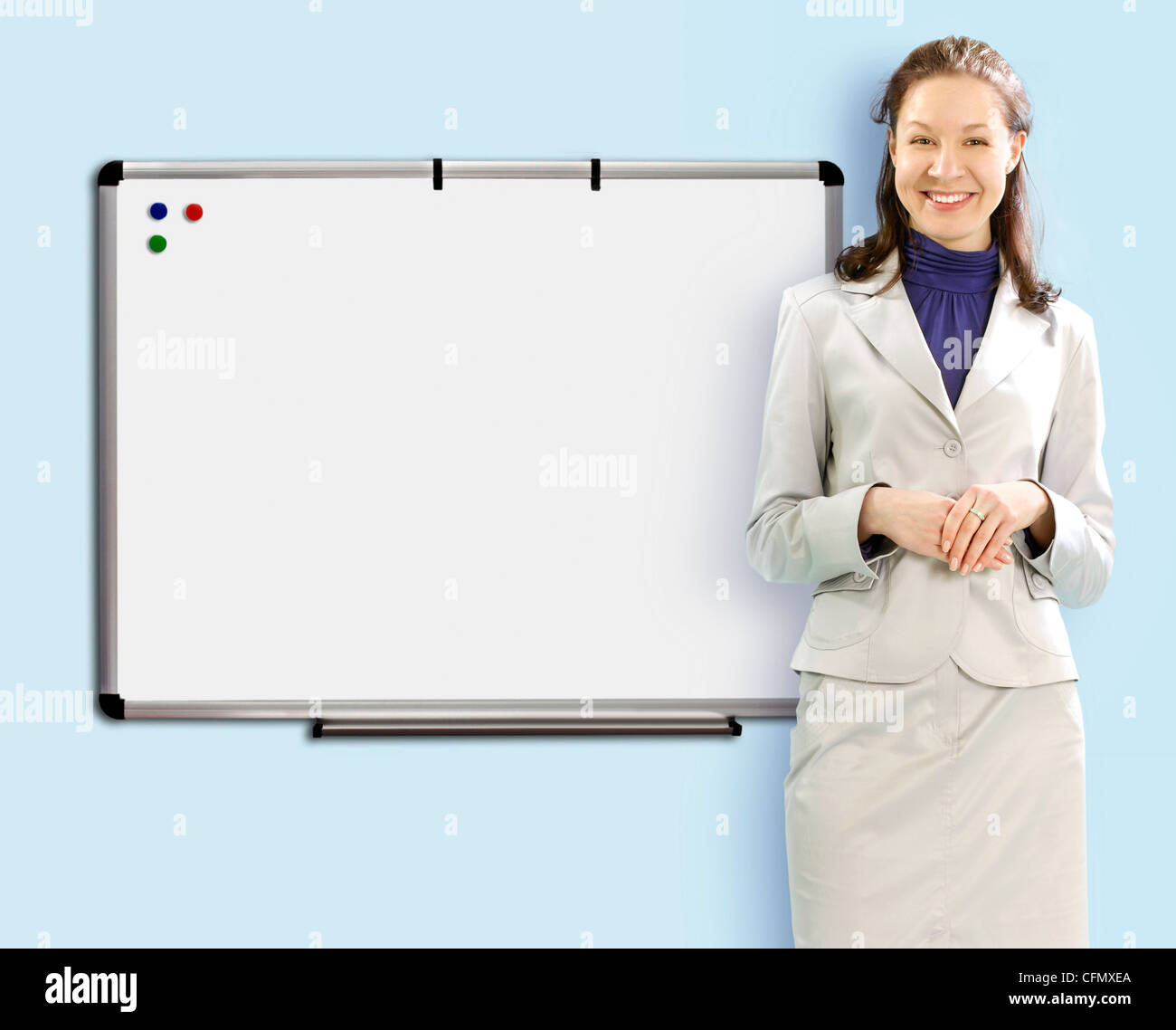 Smiling teacher près de conseil scolaire en costume blanc Banque D'Images