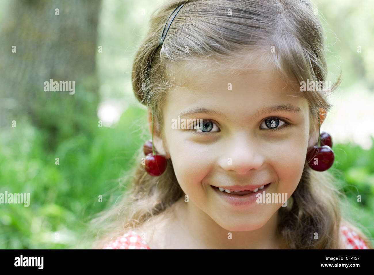 Fille avec des cerises ses oreilles Banque D'Images