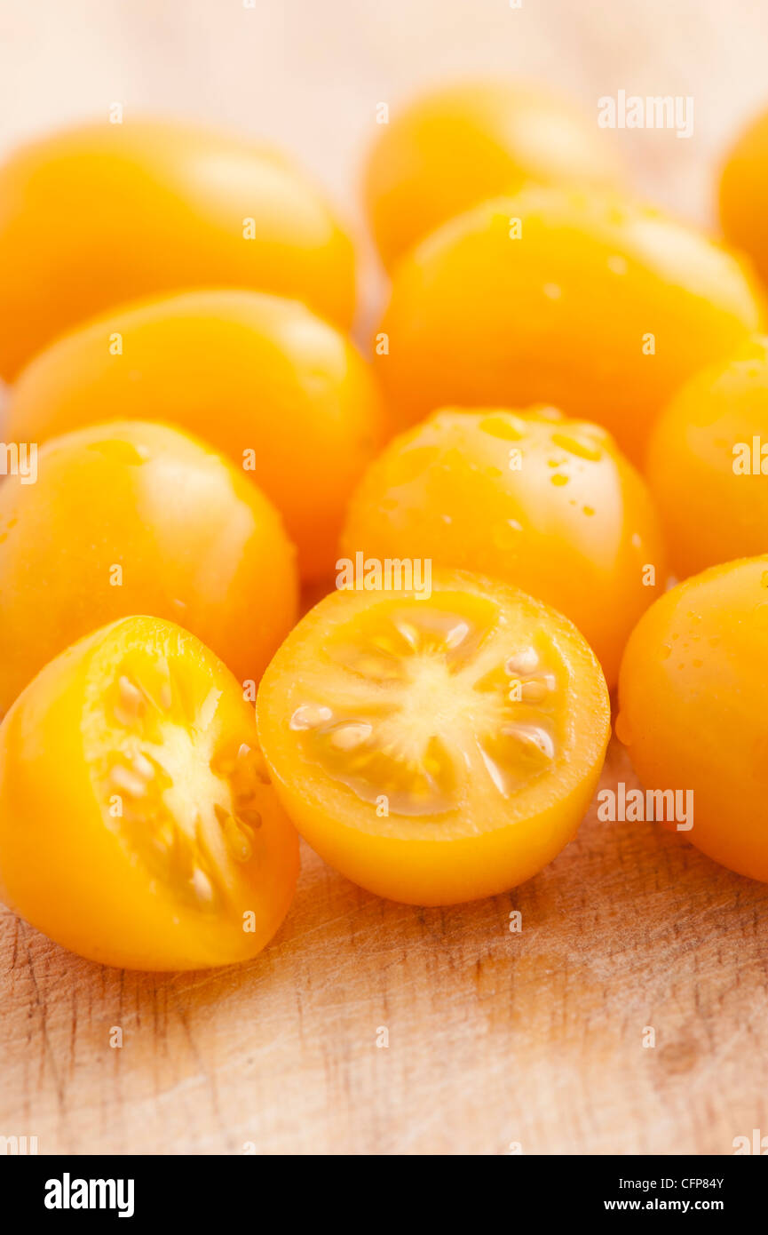 Les tomates de prune jaune sur une planche à découper Banque D'Images