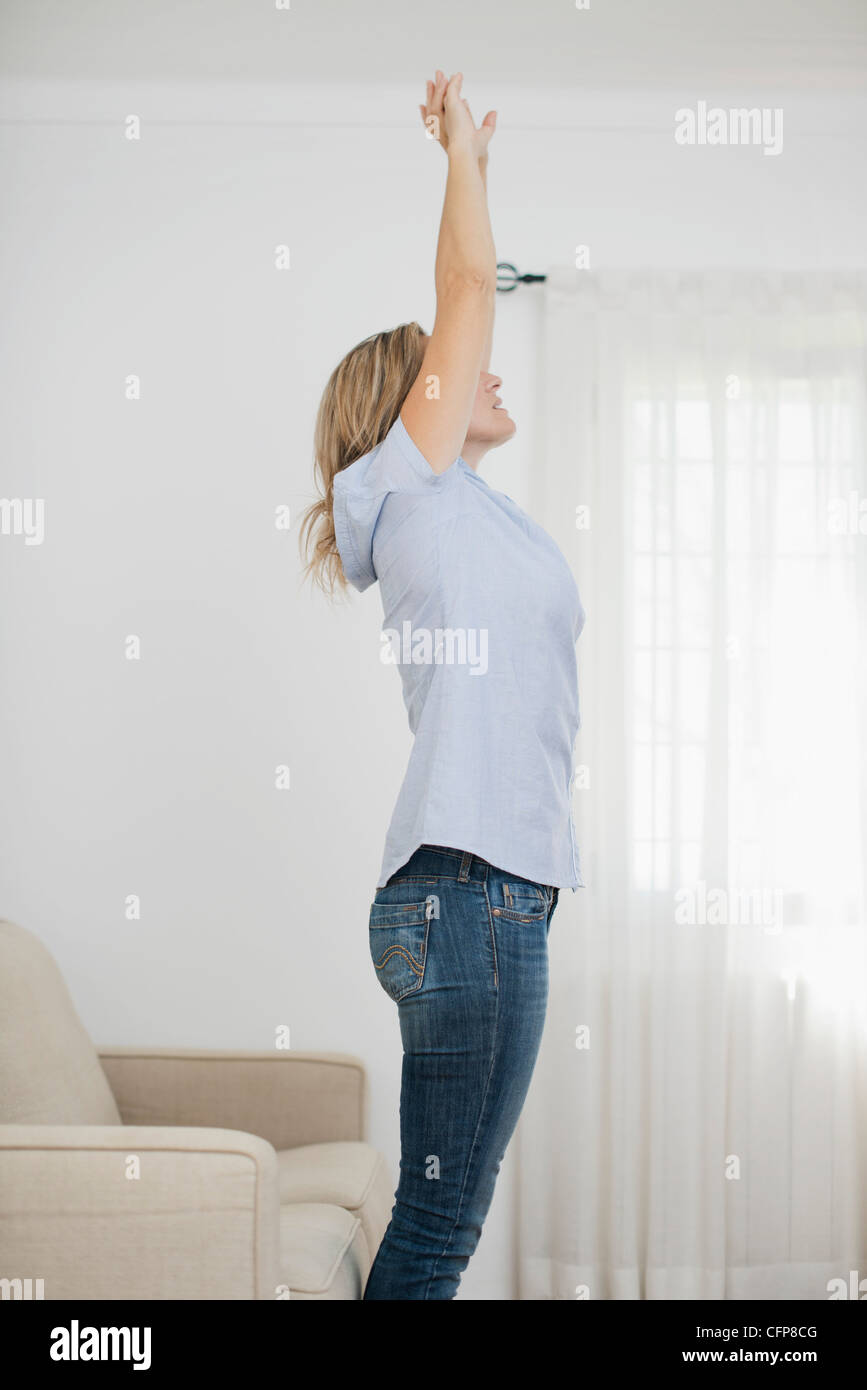 Woman stretching in living room Banque D'Images