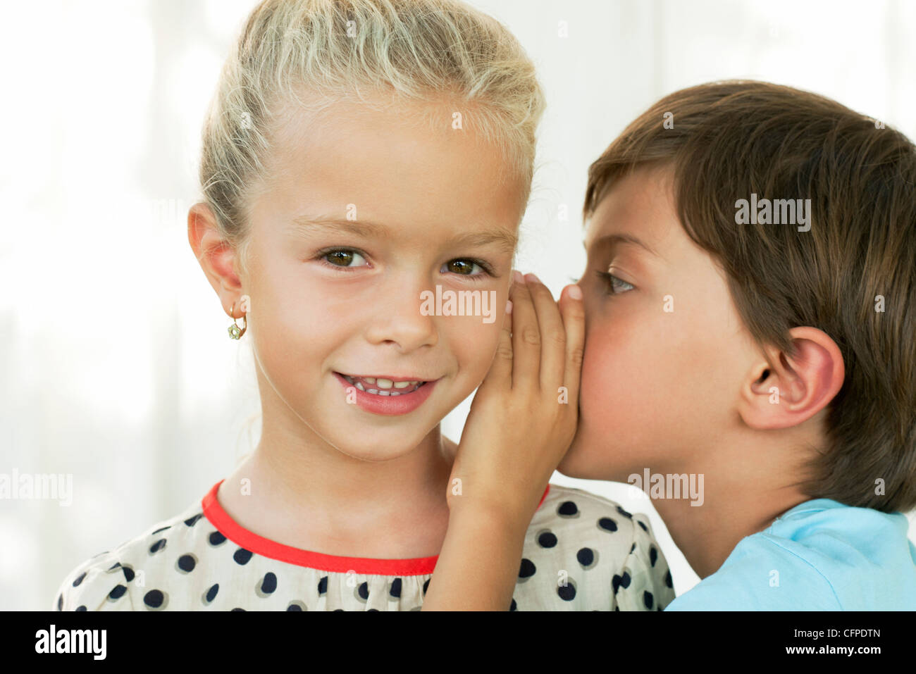 Garçon chuchoter dans l'oreille de la jeune fille Photo Stock - Alamy