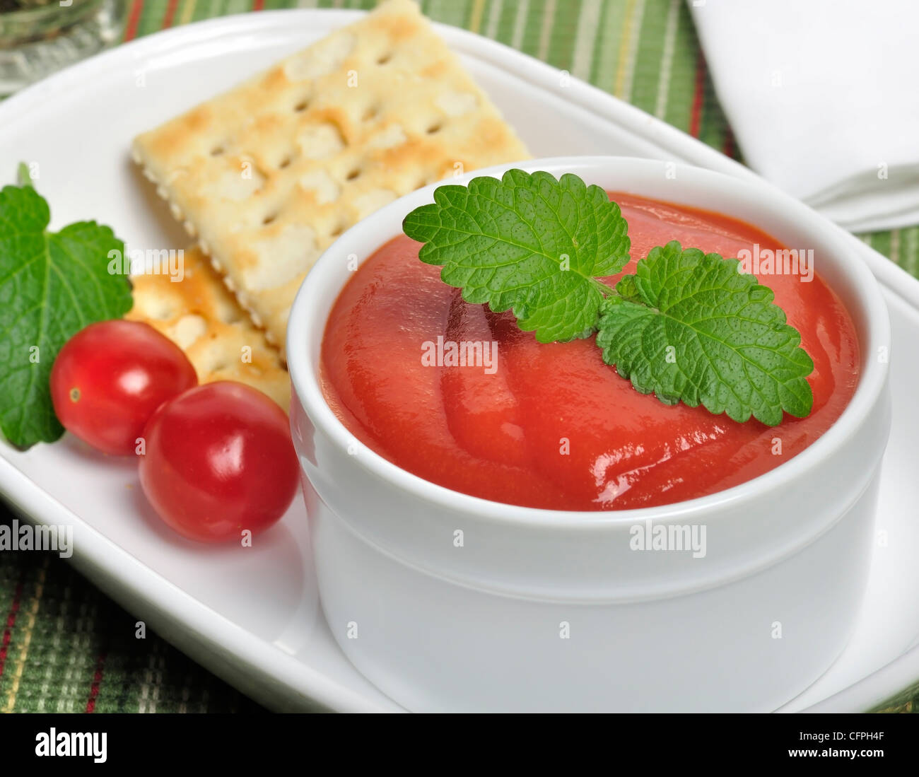Soupe de tomate dans un bol blanc avec craquelins et épices Banque D'Images