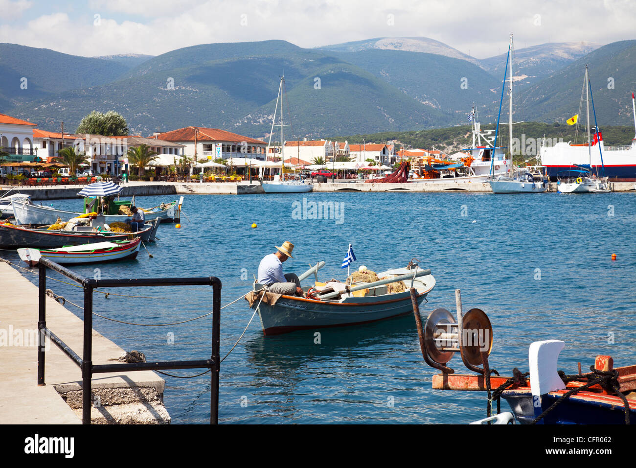 Vieux Pêcheur typique grec vaquant à ses filets de pêche tout en restant sur son bateau pour les prochaines jours voyage à Kefalonia Banque D'Images