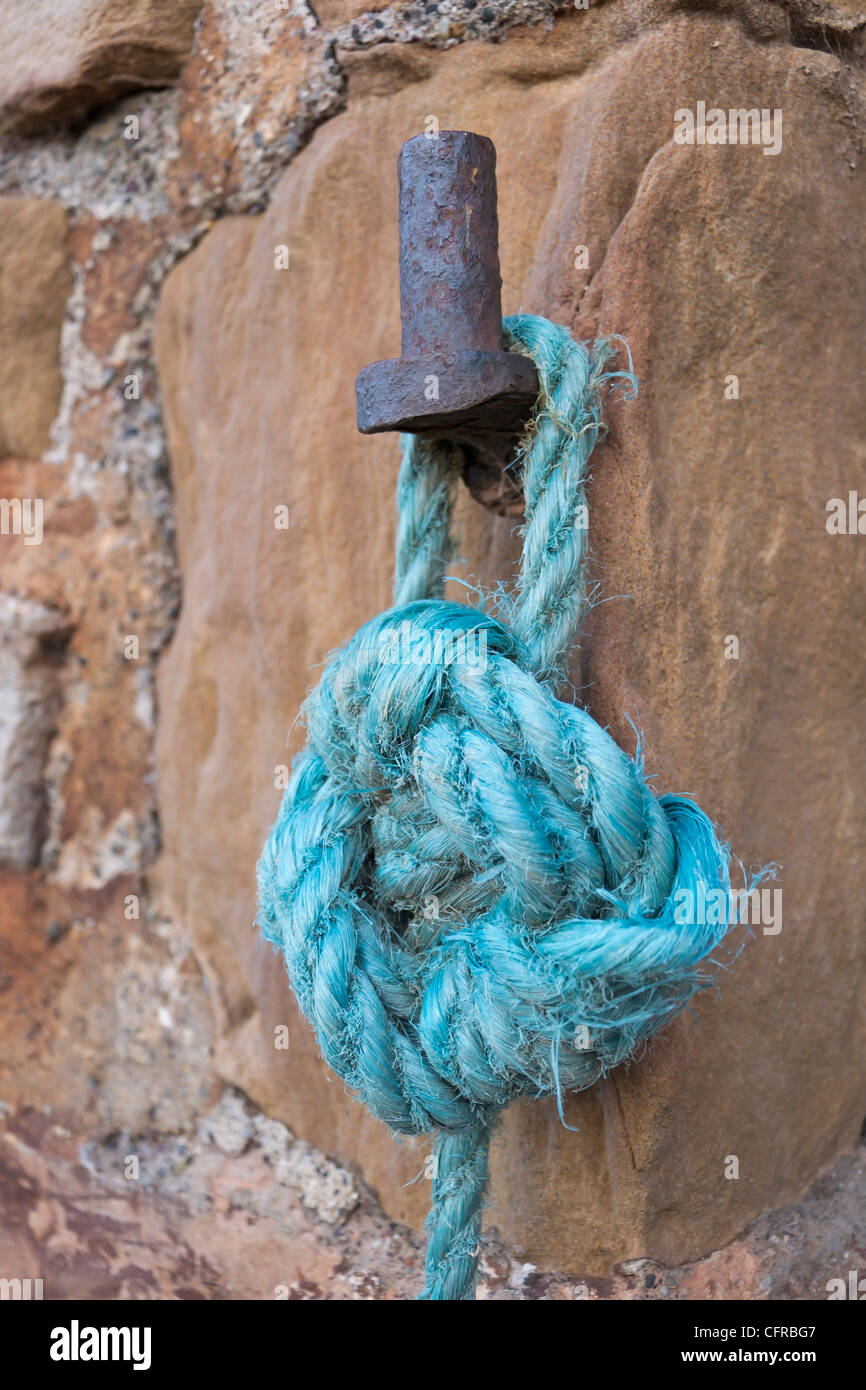 Amarre nylon bleu lié à un vieux fer à repasser fixation sur un mur du port. Banque D'Images