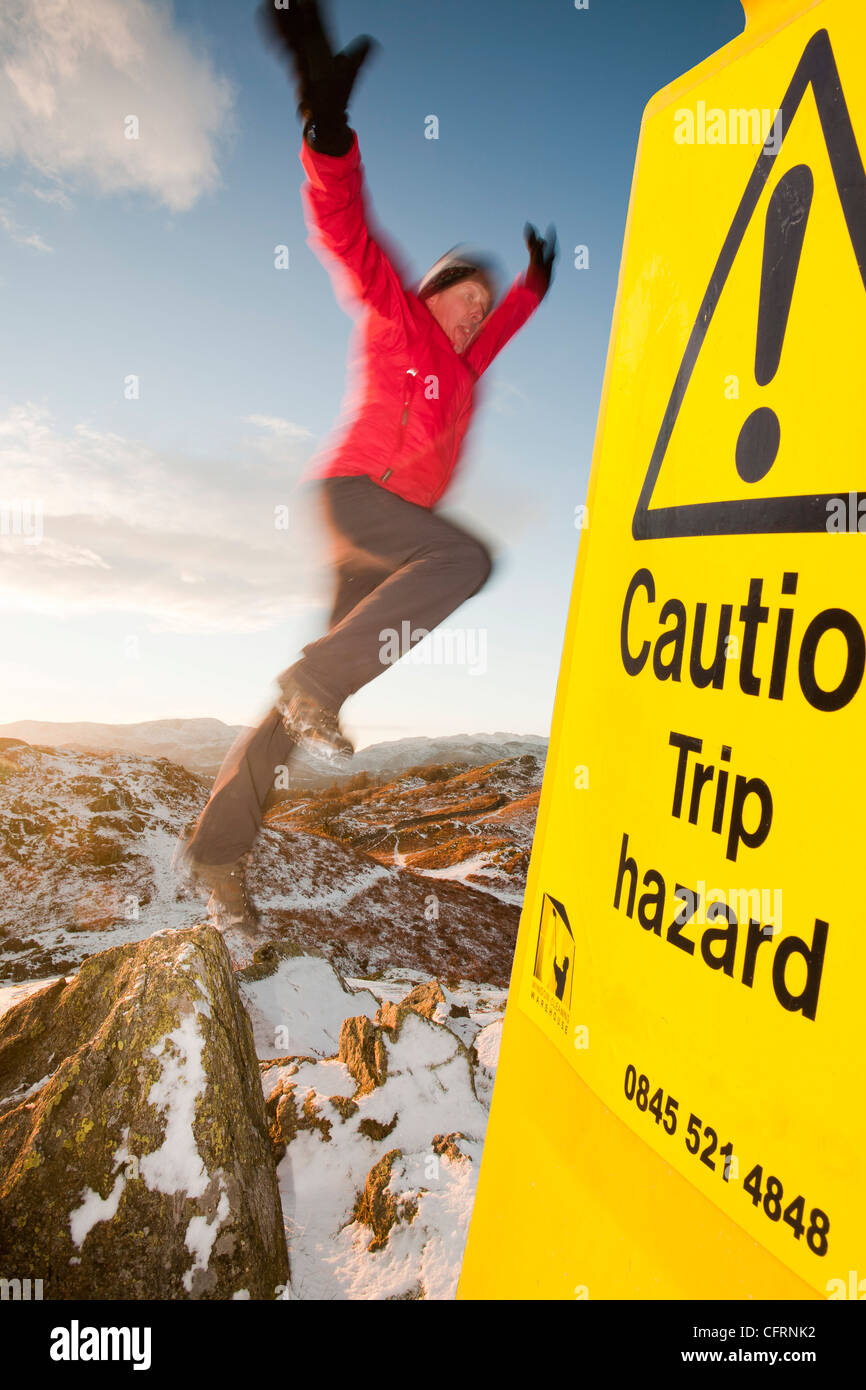 L'alpiniste sur Todd Crag summit dans le Lake District, UK, au crépuscule et trébuchement signe. Banque D'Images