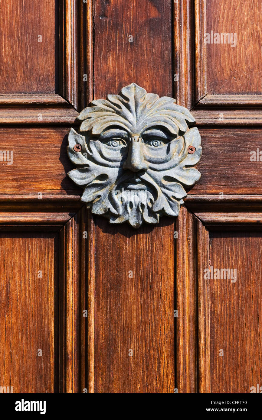 Green Man doorknocker sur une porte en bois. Banque D'Images