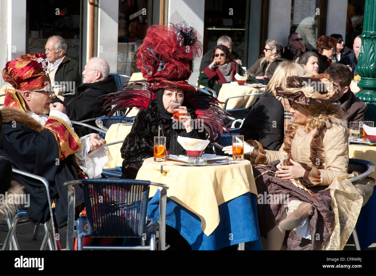 Trois personnes habillées en costume de carnaval assis à une table de la chaussée dans un café à Venise Italie Banque D'Images