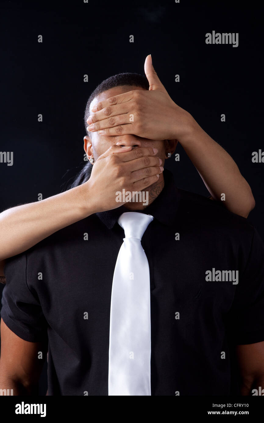 Bel homme noir, avec une cravate blanche et les mains couvrant ses yeux et  de la bouche, entouré par un fond noir Photo Stock - Alamy
