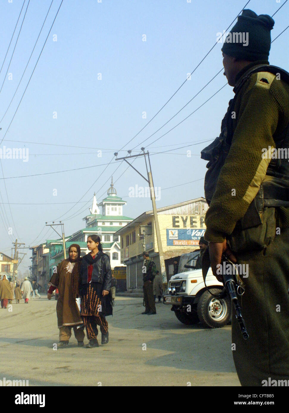 Personnel force paramilitaire indien monte la garde sur place en tant que femmes passer devant lui à la suite d'une explosion dans le centre-ville de Srinagar, la capitale d'été du Cachemire indien, le vendredi, 29 décembre 2006. Shabir Hussain Khan, un civil du Cachemire, qui était une moto, a été tué sur le coup lorsque t Banque D'Images