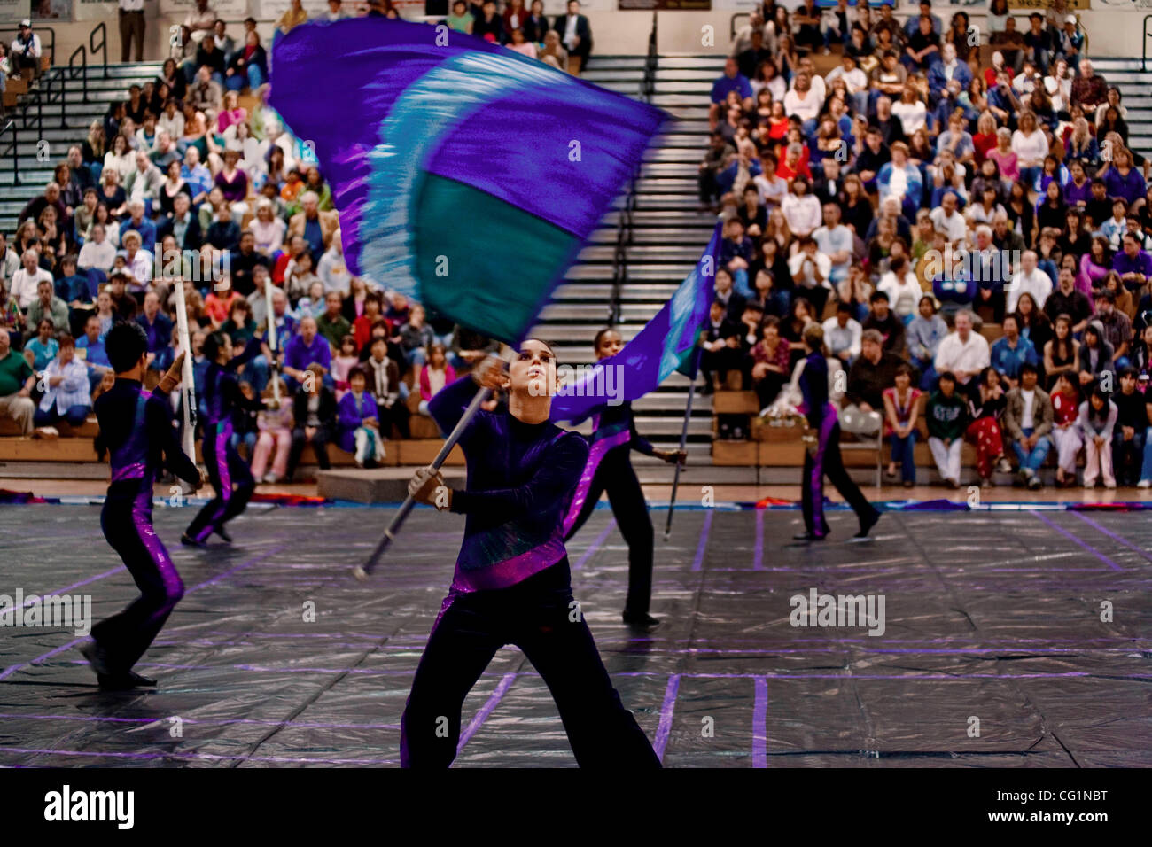 Twirling bannières colorées, femelle couleur garde côtière ont un rendement d'band concert étudiant dans un Fountain Valley, CA, de l'école secondaire d'un gymnase. Banque D'Images