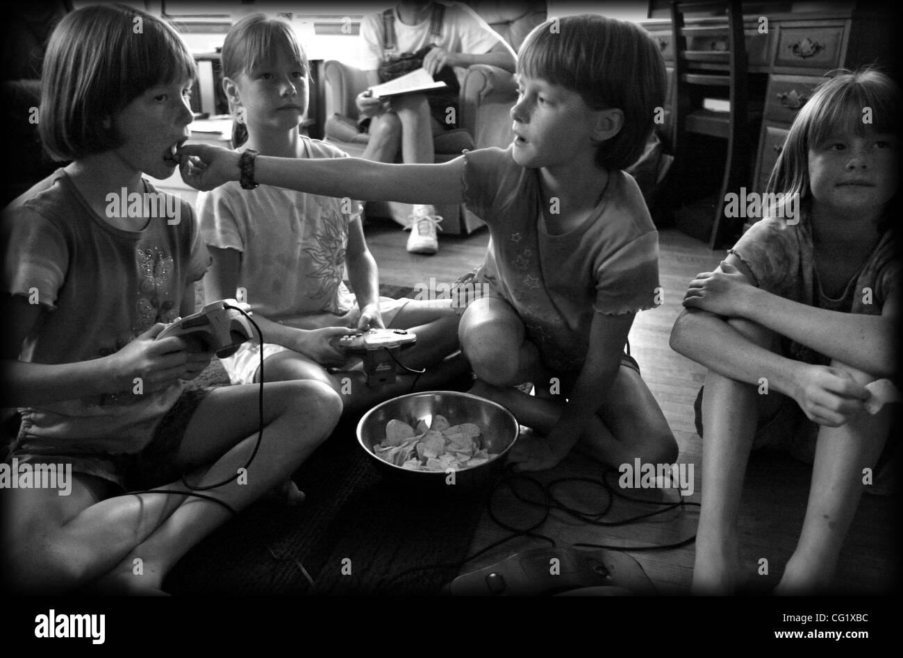 Buffalo, MN 7/14/2003 Le Durst quadruplés. L'un des avantages d'avoir trois sœurs autour est lorsque vous avez besoin d'une puce alors que vous jouez à un jeu vidéo que vous obtenez le service alimentaire. Megan, Kendra, Sarah et Calli jouer a un jeu vidéo et manger chips. (Crédit Image : © Minneapolis Star Tribune/ZUMA Press) Banque D'Images