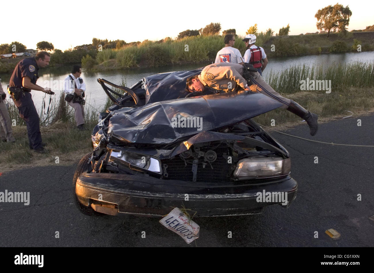 California Highway Patrol Officer Mike Sullivan donne sur une voiture tirée de la rivière Sacramento, mardi après-midi. Une personne est morte et une autre a été hospitalisé après que le véhicule qu'ils étaient en plongée dans la rivière Sacramento Walnut Grove mardi après-midi, les autorités ont dit. La fatale Banque D'Images