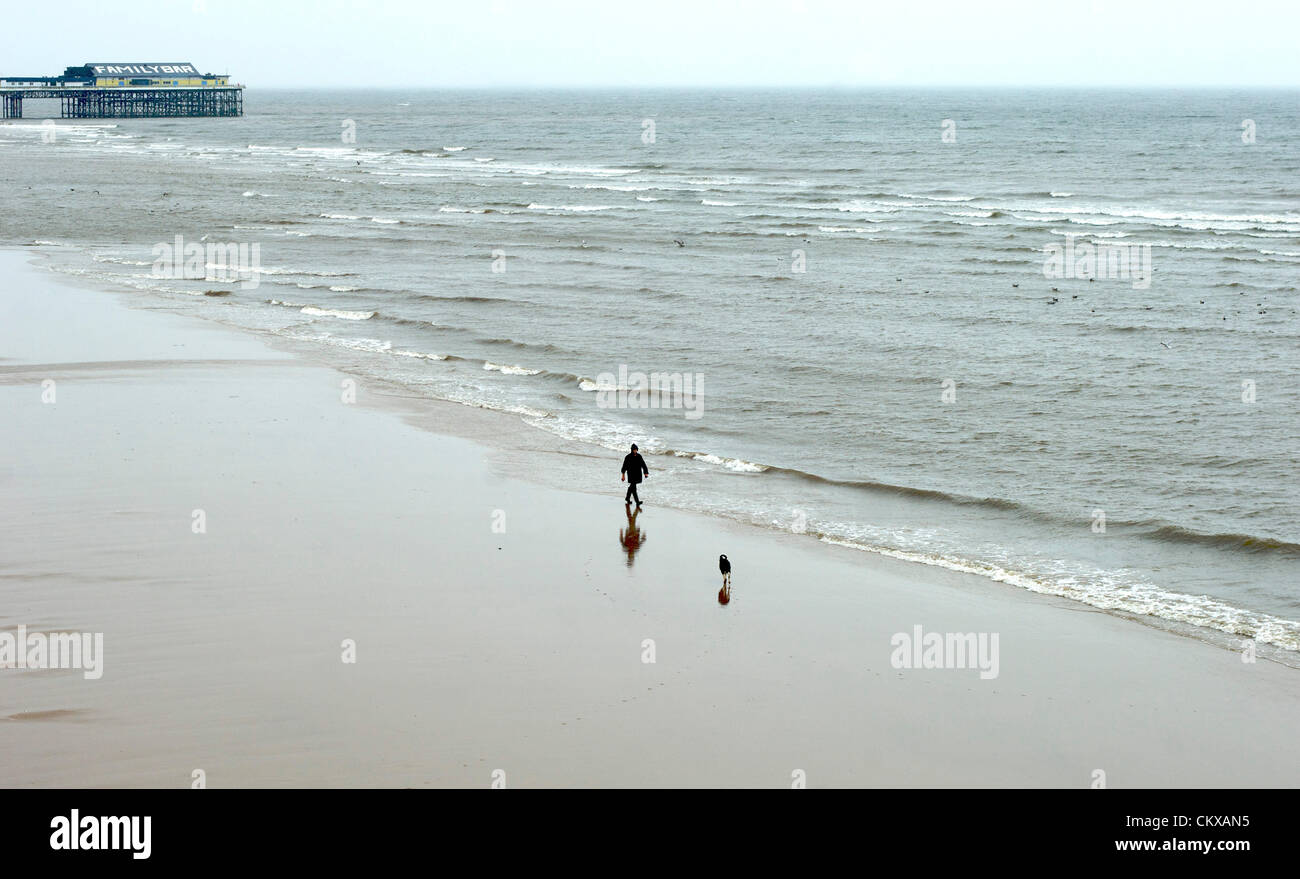 27 août 2012 pluvieux et venteux météo à Blackpool sur le dernier été de la banque de l'année, gardé la maison de foule. Un homme courageux et son chien à pied le long de la plage vide dans la station. Crédit : Kevin Walsh / Alamy Live News Banque D'Images