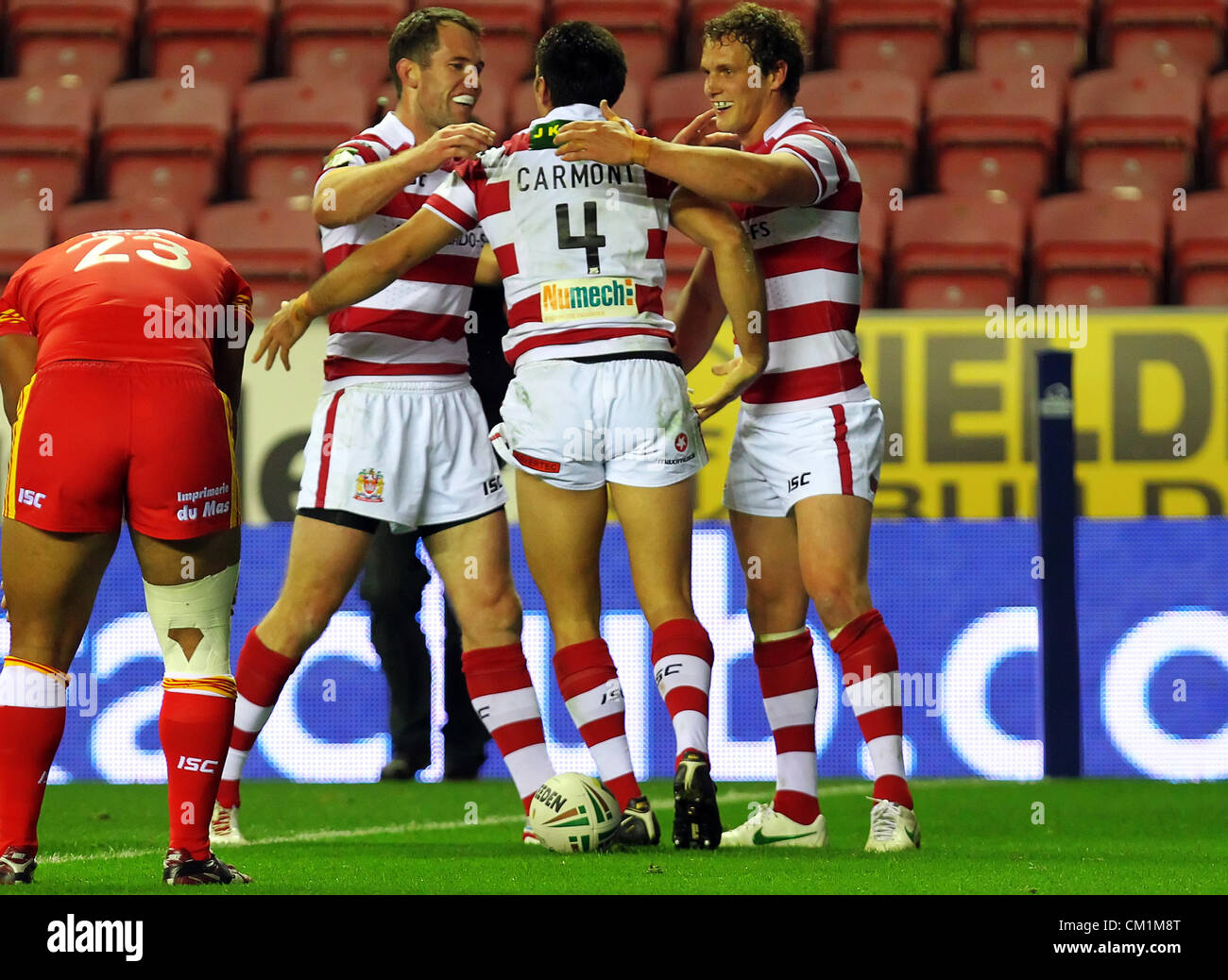 14.09.2012 Wigan, Angleterre. La ligue de rugby. Wigan Warriors v des Dragons Catalans . Wigan Warriors Nouvelle-zélande Centre George Carmont plonge à travers la ligne de marquer son tour du chapeau, essayez en Stobart Super League jouer hors jeu joué au DW Stadium. Puis, il célèbre avec ses coéquipiers. Banque D'Images