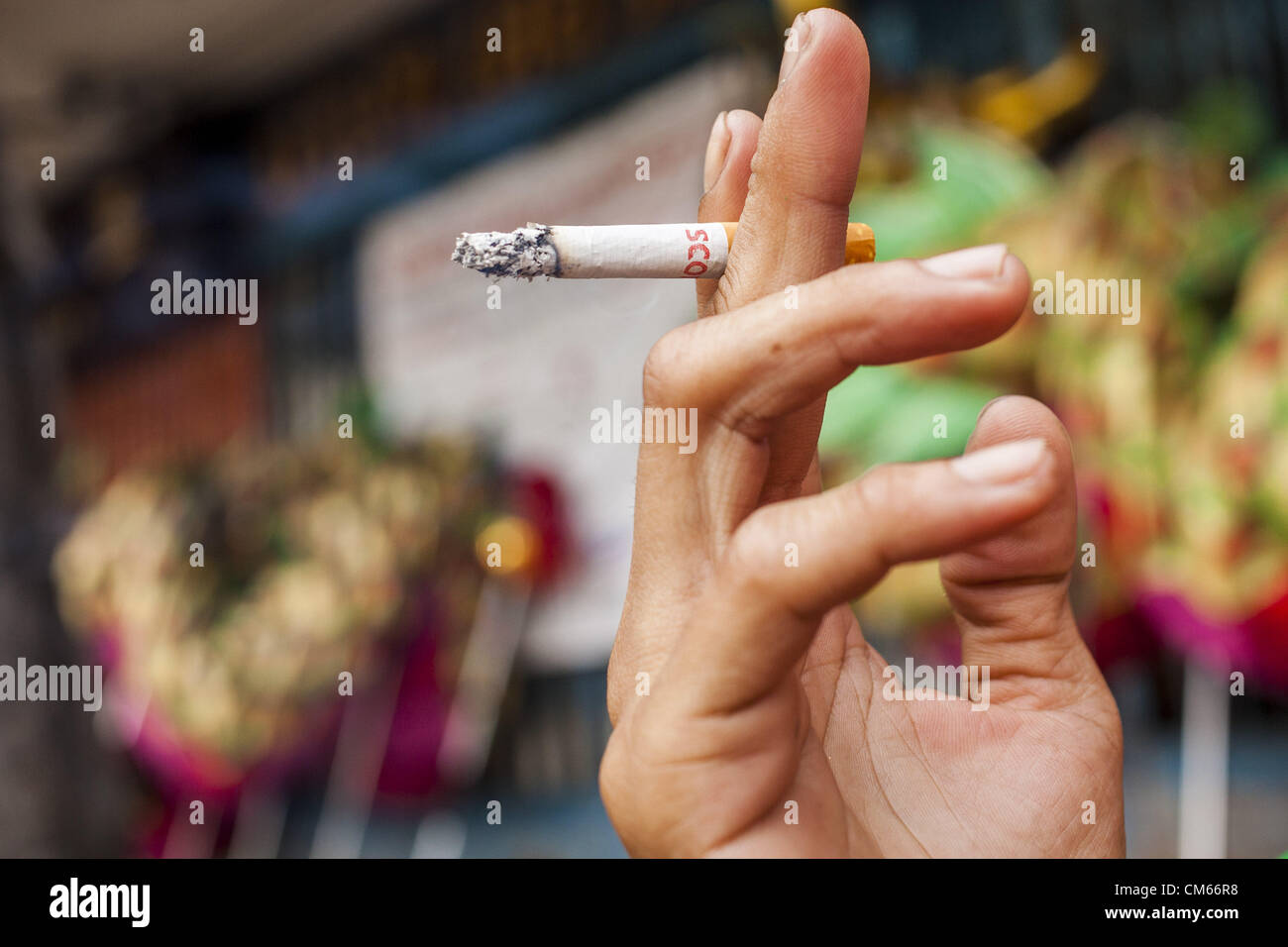 14 octobre 2012 - Bangkok, Thaïlande - Un homme est titulaire d'une cigarette tout en fumant dans une rue de Bangkok, Thaïlande. La Thaïlande et les Philippines sont impliqués dans un différend au sujet de taxes sur les cigarettes. Les responsables du commerce des Philippines allèguent que la Thaïlande une accusation injuste taxe sur les importations de cigarettes des Philippines. Les responsables thaïlandais ont répondu qu'ils ont pris la question en délibéré. Les représentants des Philippines ont déclaré qu'ils peuvent prendre la question à l'Organisation mondiale du commerce si la Thaïlande ne répond pas par le 15 octobre. (Crédit Image : © Jack Kurtz/ZUMAPRESS.com) Banque D'Images