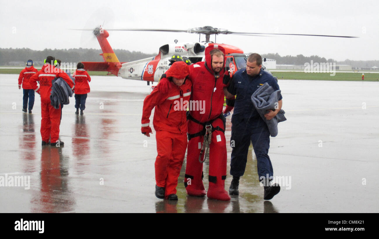 Elizabeth City, Caroline du Nord, USA. 29 octobre 2012. Les membres de la Garde côtière canadienne d'aider un des marins du le grand voilier Bounty après son arrivée à bord d'un hélicoptère de sauvetage Jayhawk MH-60, 29 octobre 2012 Elizabeth City, NC. Les équipages de la Garde côtière ont hissé 14 survivants de la Bounty après que les survivants ont abandonné le navire lorsqu'il a commencé à prendre de l'eau sur 90 kilomètres au sud-est du cap Hatteras pendant l'Ouragan Sandy. Banque D'Images