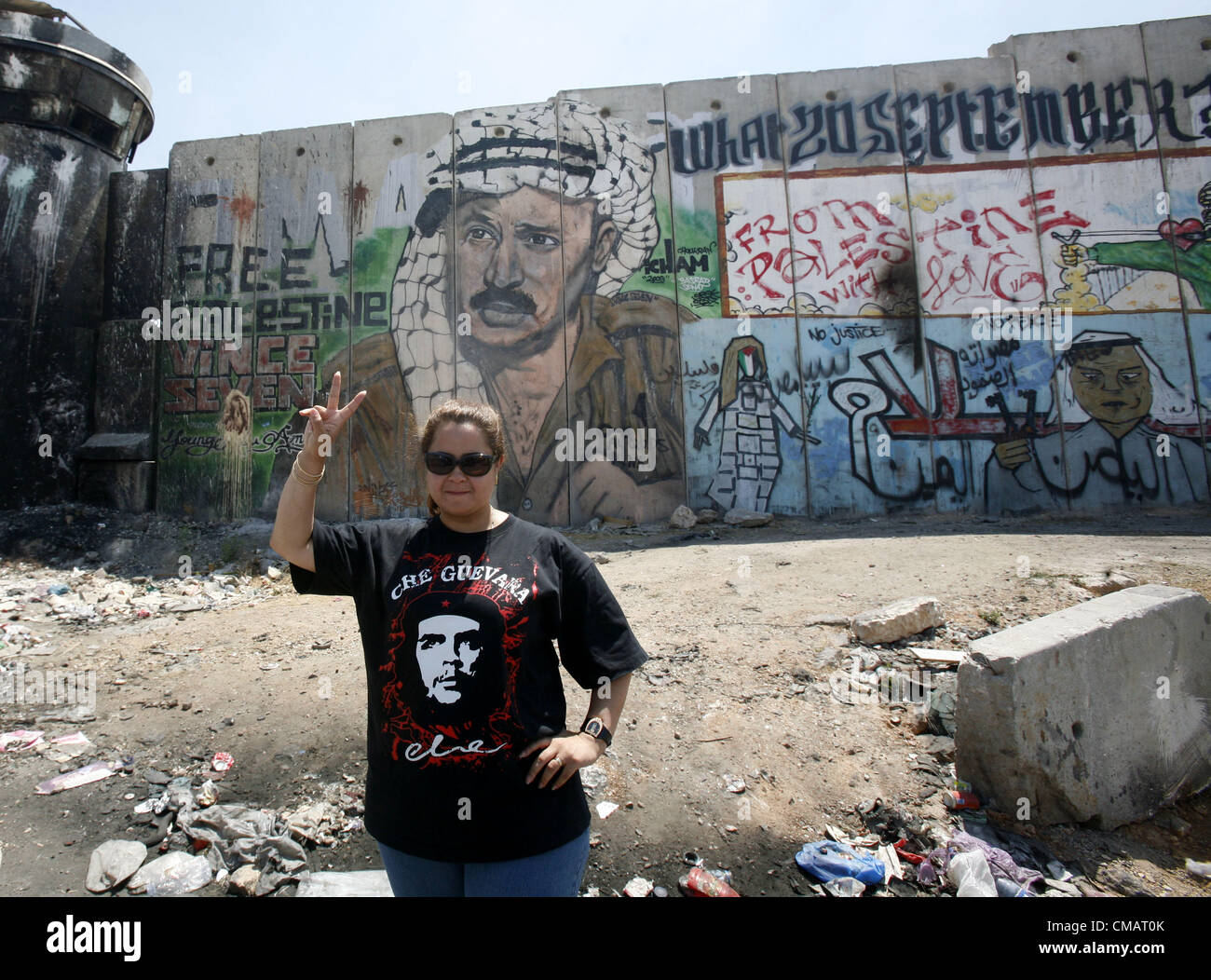 6 juillet 2012 - Jérusalem, Jérusalem, territoire palestinien - une femme égyptienne portant un T-shirt avec portrait de Argentinian-Cuban Che Guevara guérilla pose pour une photo devant une peinture murale de la fin du leader palestinien Yasser Arafat sur une section de la barrière de séparation controversée au checkpoint de Qalandia, entre Jérusalem et Ramallah le 6 juillet 2012. Les Palestiniens sont à la recherche d'une sonde international dans la mort de Yasser Arafat pour enfin ''fermer le fichier'' sur sa mort mystérieuse (crédit Image : © Mahfouz Abu Turk/APA Images/ZUMAPRESS.com) Banque D'Images
